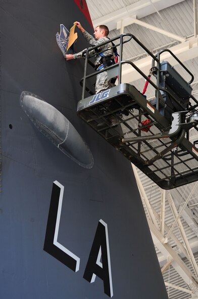 BARKSDALE AIR FORCE BASE, La. -- Airman 1st Class Brandon Clark, 2d Maintenance Squadron aircraft structural maintenance technician removes the Air Combat Command shield from the tail of a B-52H Stratofortress to reveal a new Air Force Global Strike Command shield following the wing transition. Switching shields can take up to two hours to accomplish, and the temperature of the aircraft must be higher than 45 degrees for the shield to adhere properly. (U.S. Air Force photo Senior Airman Joanna M. Kresge)