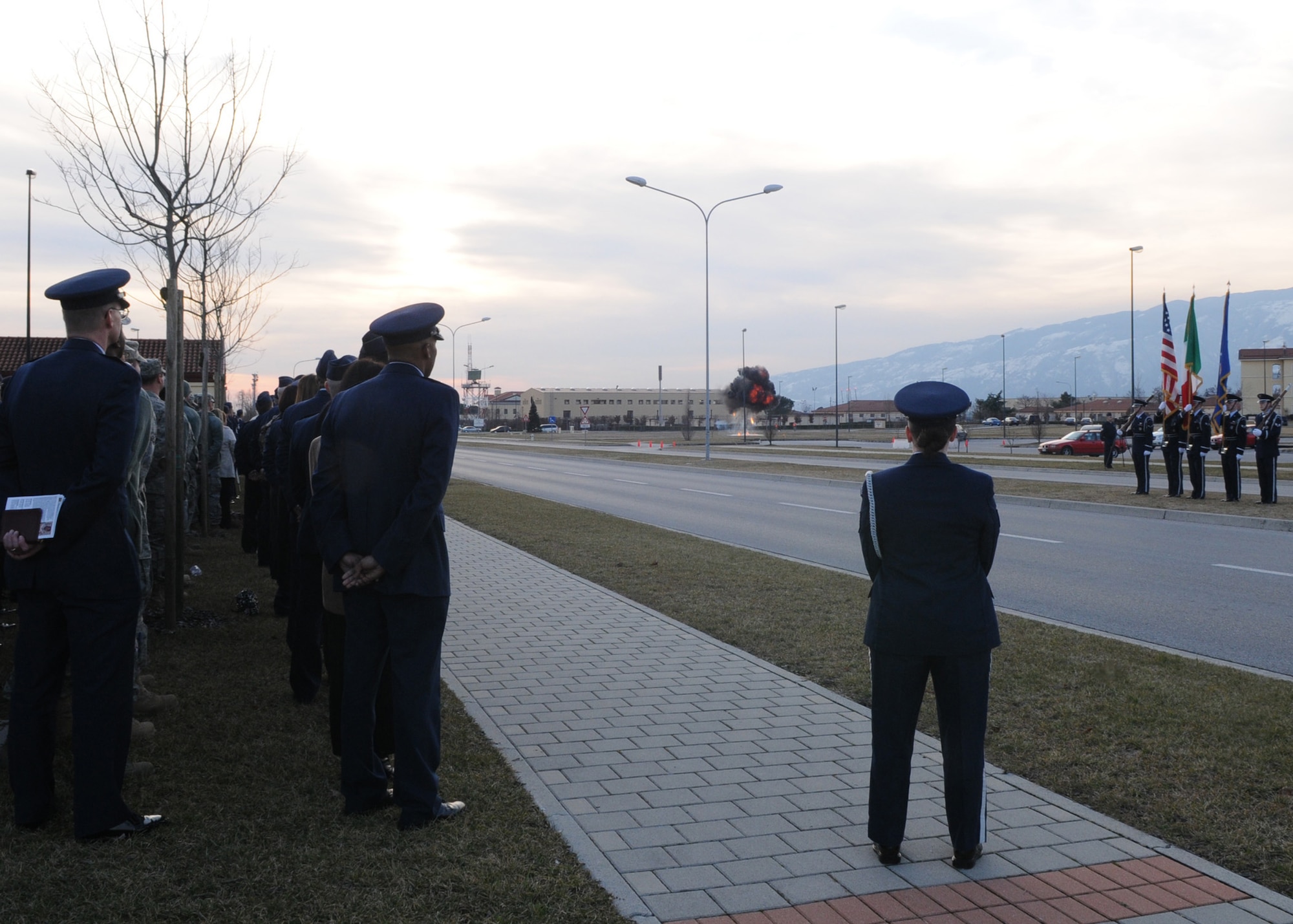Members of the 31st Fighter Wing watch as a final controlled detonation occurs during the memorial service for Tech. Sgt. Adam K. Ginett held Feb. 1, 2010, at Aviano Air Base, Italy. The memorial service honors Sergeant Ginett, a Knightdale, N.C. native, who died Jan. 19 near Kandahar Air Field, Afghanistan, of wounds suffered from an improvised explosive device. He was assigned to the 31st Civil Engineer Squadron explosive ordnance disposal flight at Aviano AB, Italy. (U.S. Air Force photo/Staff Sgt. Mercedes Crossland)
