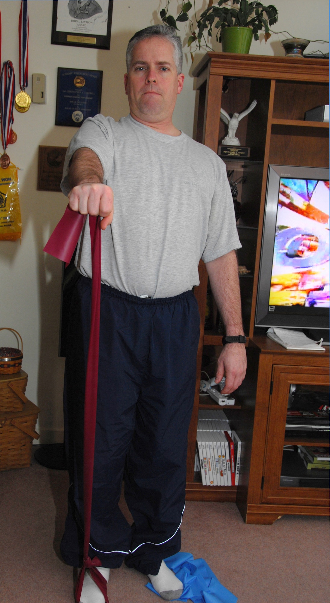 ROYAL AIR FORCE LAKENHEATH, England -- Tech. Sgt. Christopher Campbell, 48th Fighter Wing Public Affairs program manager, uses a theraband to strengthen his shoulder as part of his physical therapy at home Jan. 24. Sergeant Campbell has several exercises to aid his recovery from shoulder surgeries; this particular motion is designed to work the flexibility in his shoulder. This exercise will increase his range of motion and strengthen his deltoid muscles. (U.S. Air Force photo/Alexander Campbell) 