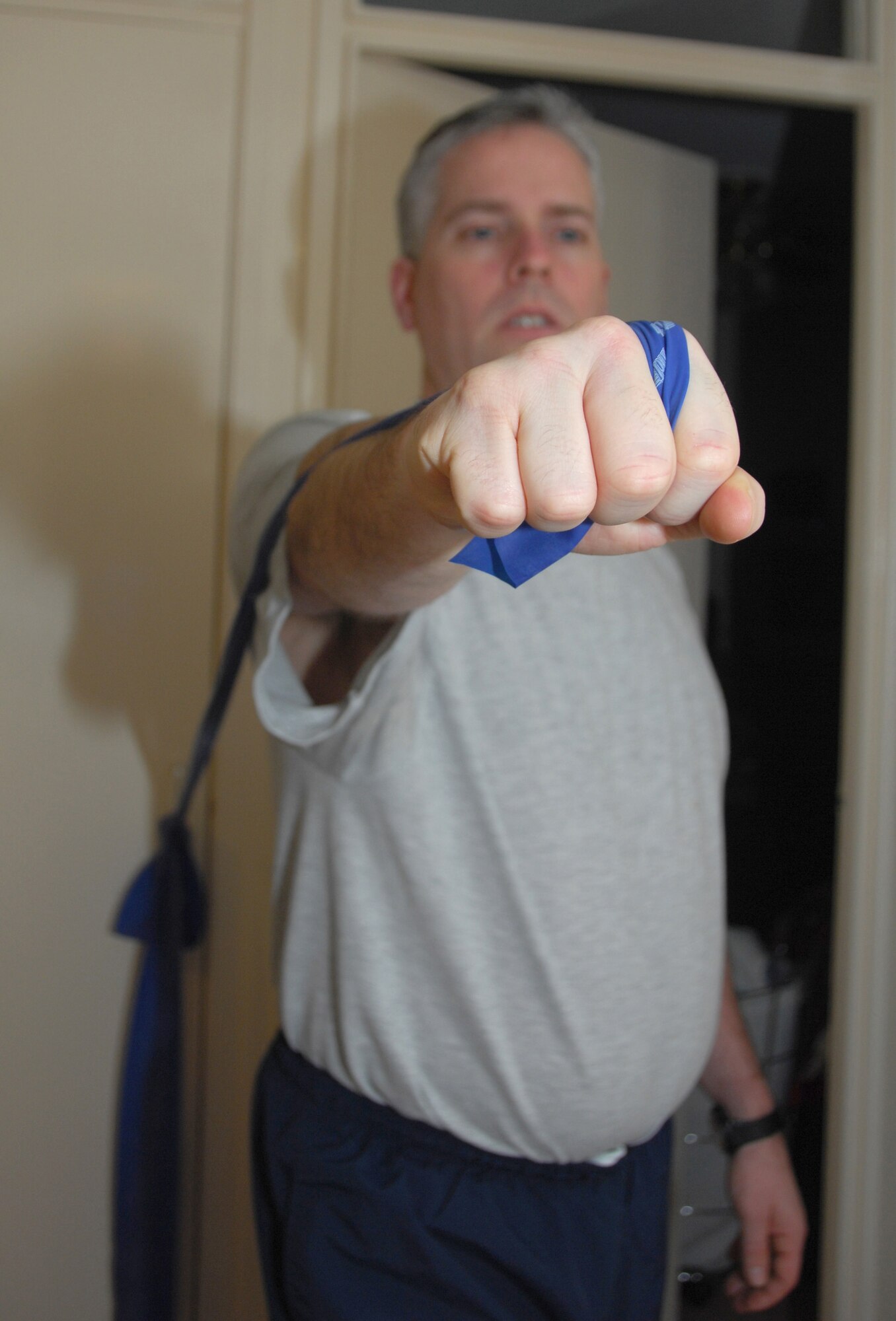 ROYAL AIR FORCE LAKENHEATH, England -- Tech. Sgt. Christopher Campbell, 48th Fighter Wing Public Affairs program manager, uses a theraband to strengthen his shoulder muscles as part of his physical therapy at home Jan. 24. Sergeant Campbell has several exercises to aid his recovery from shoulder surgeries; this particular motion is designed to work muscles around the shoulder. Sergeant Campbell has to lunge forward with the band in his hand, keep his arm parallel to the ground and at the end of the lunge push forward a little more to finish the exercise. (U.S. Air Force photo/Alexander Campbell) 