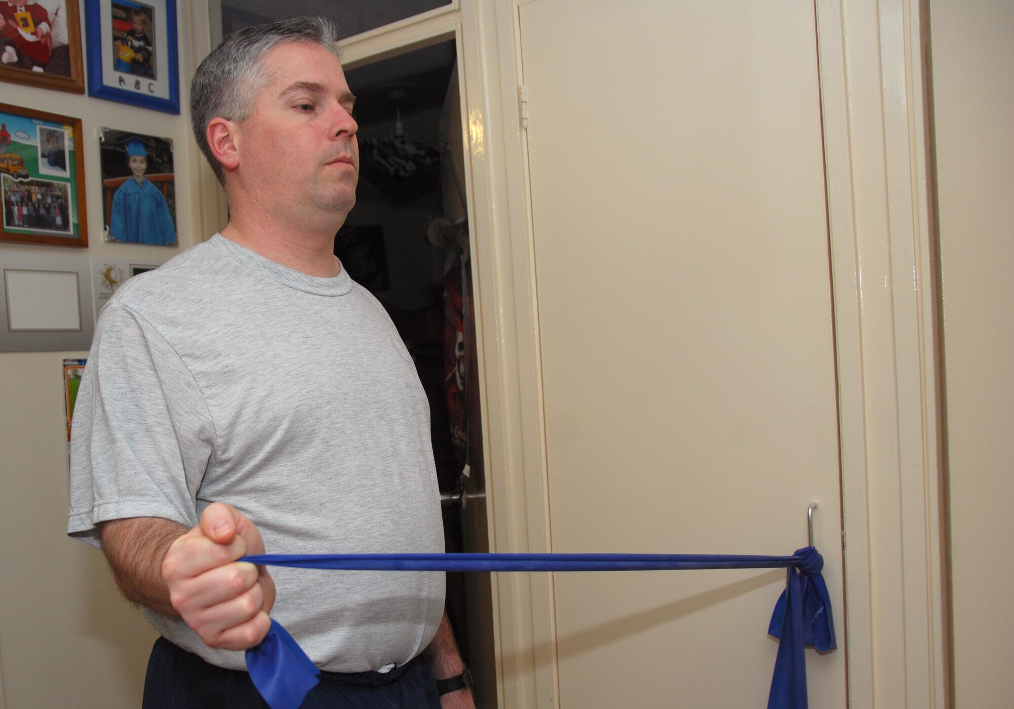 ROYAL AIR FORCE LAKENHEATH, England -- Tech. Sgt. Christopher Campbell, 48th Fighter Wing Public Affairs program manager, uses a theraband to strengthen muscles as part of his physical therapy at home Jan. 24. Sergeant Campbell is using this exercise to strengthen the muscles in his shoulder. He has to perform three sets of ten for each shoulder. (U.S. Air Force photo/Alexander Campbell)