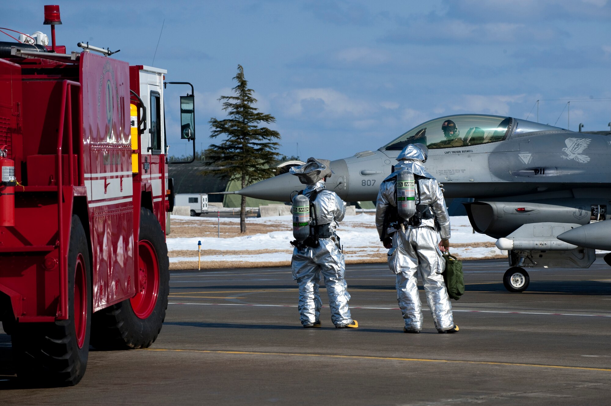 MISAWA AIR BASE, Japan -- Firemen from the 35th Civil Engineer Squadron wait for an F-16 Fighting Falcon to power down before assessing potential fire hazards during a simulated in-flight emergency on the flightline Feb. 2. After the jet was shut down and deemed safe, weapons systems maintainers moved in to fix the simulated gun jam. (U.S. Air Force photo/Staff Sgt. Samuel Morse)