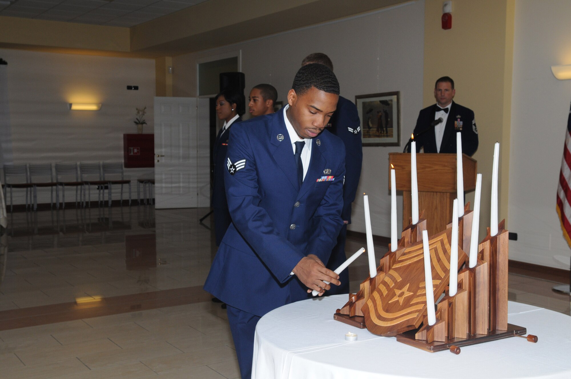 Senior Airman Andre Alexander, 31st Civil Engineer Squadron, lights the fourth candle representing the Senior Airman  tier during the candle lighting ceremony at the Chief Master Sergeant Recognition Ceremony  Jan. 30, 2010 in Aviano, Italy. Chiefs represent the top one percent of the enlisted force. (U.S. Air Force photo/Staff Sgt. Mercedes Crossland)