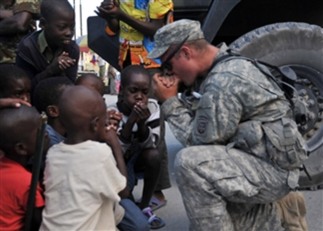 A U.S. Army soldier assigned to the 82nd Airborne Division teaches children how to two hand whistle while their families get food from the World Health Organization in Port-au-Prince, Haiti, on Jan. 31, 2010.  The United States and other international military and civilian aid agencies are conducting humanitarian and disaster relief operations as part of Operation Unified Response in the aftermath of the earthquake that hit the area on Jan. 12, 2010.  