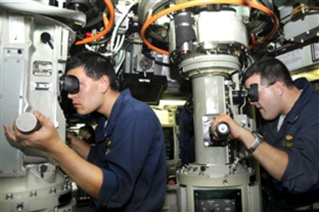 U.S. Navy Lt. j.g. John Sines, left, and Lt. Andres Aviles scan the horizon through periscopes aboard the attack submarine USS Santa Fe during a transit of the Pacific Ocean, Jan. 29, 2010. Sines is a damage control assistant and Aviles is a navigation operation officer.