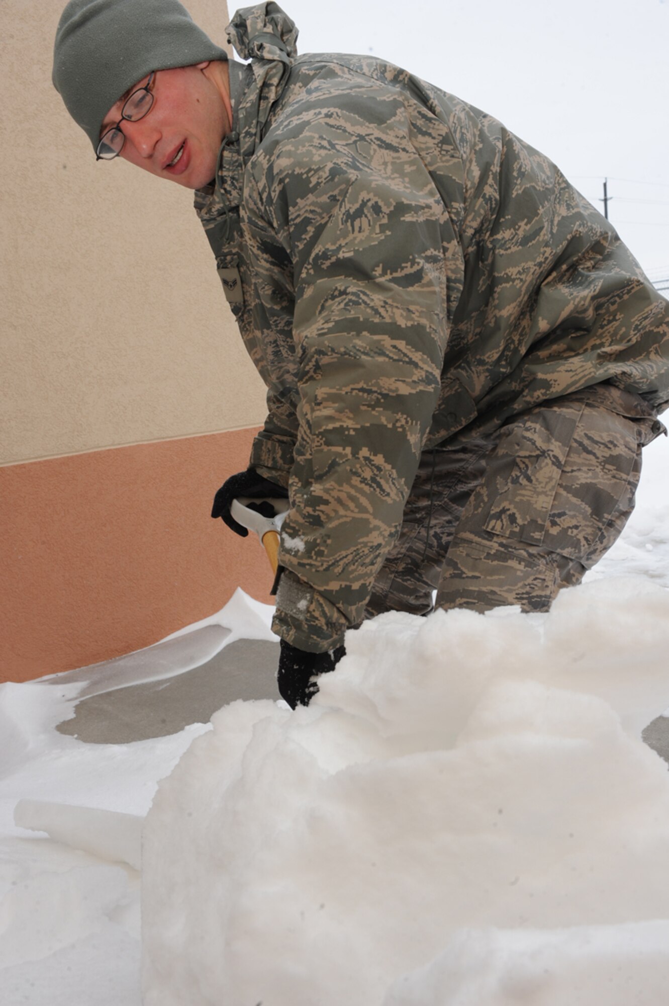 Airman 1st Class Robert Sirvid, 28th Civil Engineer Squadron pest management journeyman, scoops up snow in front of the Pest Management office, Feb 5. Ellsworth received 6 inches of snow on Feb. 4. (U.S. Air Force photo/Senior Airman Adam Grant)