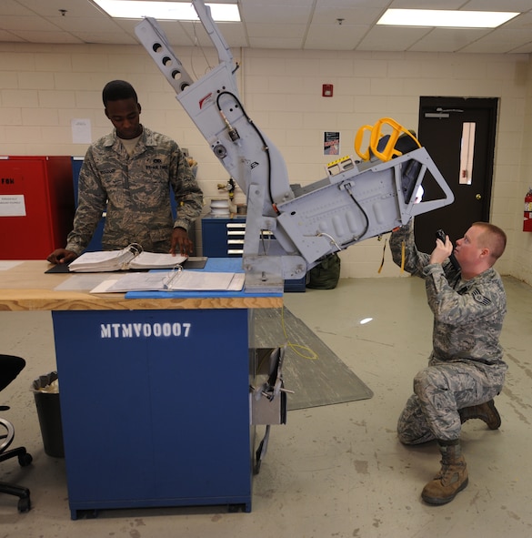 MOODY AIR FORCE BASE, Ga. -- Staff Sgt. Bryan Flaherty, 476th Fighter Group Air Reserve technician, observes the bottom of an ejection seat of an A-10C Thunderbolt II while Airman Basic Drake Hoogdorp, 23rd Component Maintenance Squadron Egress section apprentice, reads a technical order during a routine check here Feb. 3. Sergeant Flaherty and Airman Hoogdorp work together as a team to ensure that the seat is inspected properly in accordance with technical orders. (U.S. Air Force photo by Airman 1st Class Benjamin Wiseman)