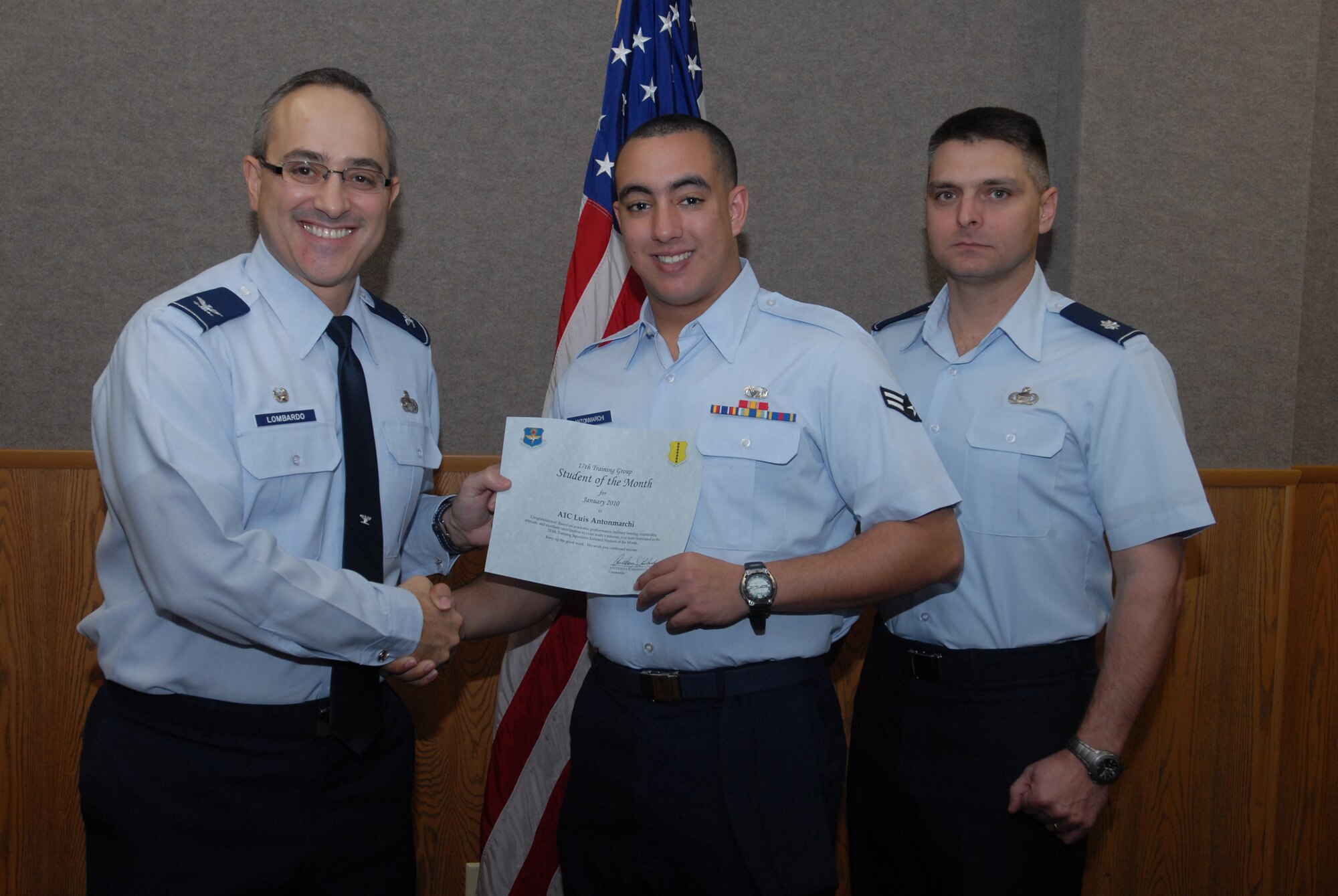 Col. Anthony Lombardo, 17th Training Group commander presents a Student of the Month certificate to Airman 1st Class Luis Antonmarchi, 315th Training Squadron student, Feb. 2, as  Lt. Col. Erick Lawson, 316th Training Squadron commander looks on. Every month, Goodfellow's training squadrons choose their top enlisted student, both in academic performance and in ability to meet military training standards, for recognition as Student of the Month. (U.S. Air Force photo/ Senior Airman Tong Duong)