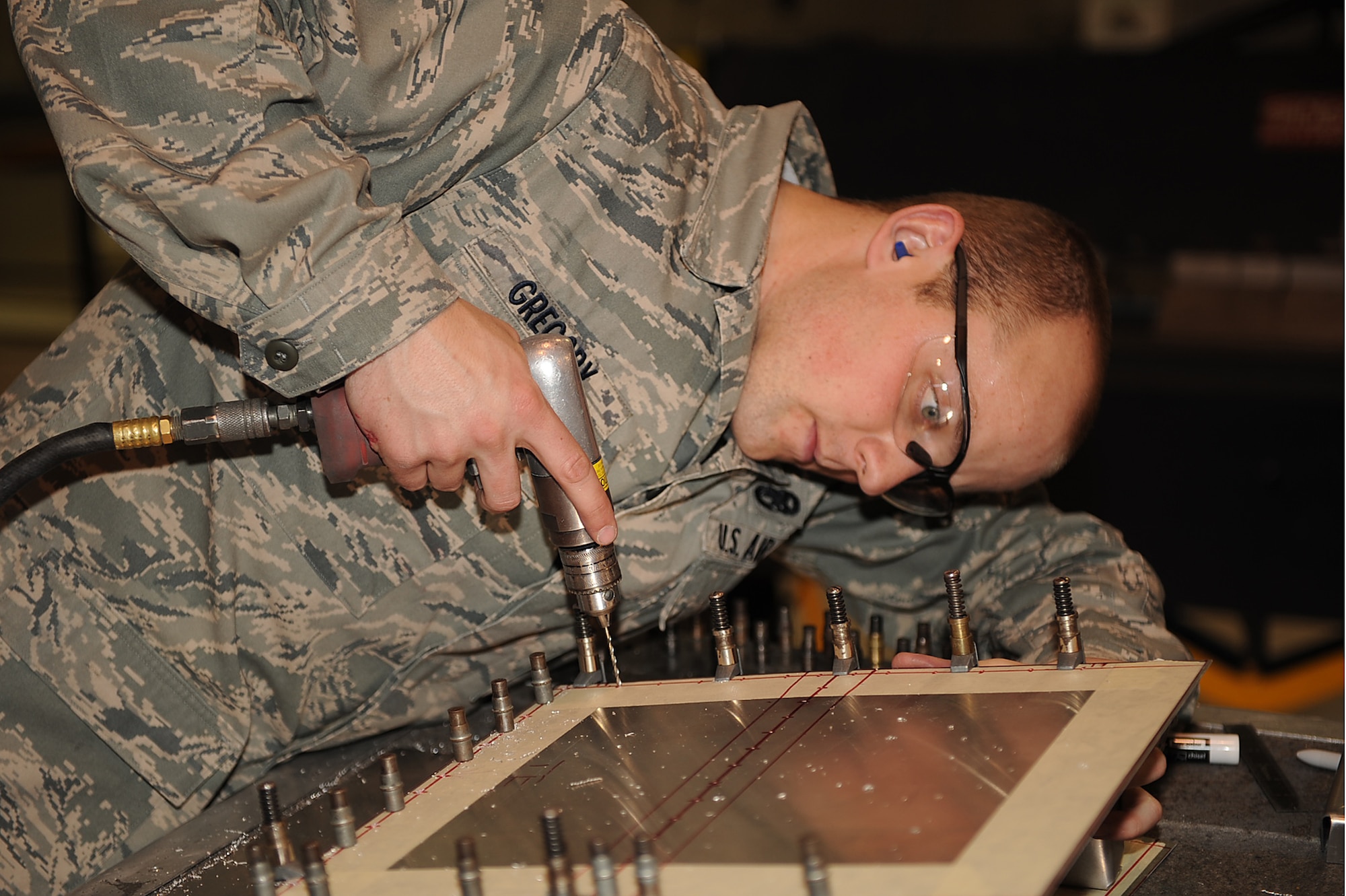Airman 1st Class Christopher Gregory, 4th Equipment Maintenance Squadron aircraft structural maintenance apprentice, drills holes into a piece of metal for fasteners to be installed during on-the-job training at Seymour Johnson Air Force Base, N.C., Feb. 3, 2010. The fasteners are used to attach to the skin of a simulated aircraft structure. Gregory hails from Eagle River, Alaska. (U.S. Air Force photo/Senior Airman Ciara Wymbs) 