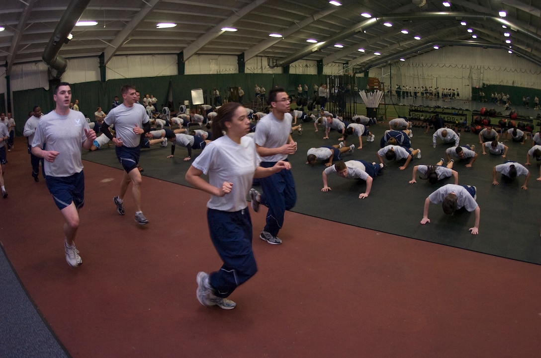 A cadre of 844th Communications Squadron members run laps around the Tactical Fitness Center as Air Force District of Washington members perform push-ups during a CrossFit class inside the West Fitness Center at Joint Base Andrews, Md., Jan. 29, 2010.