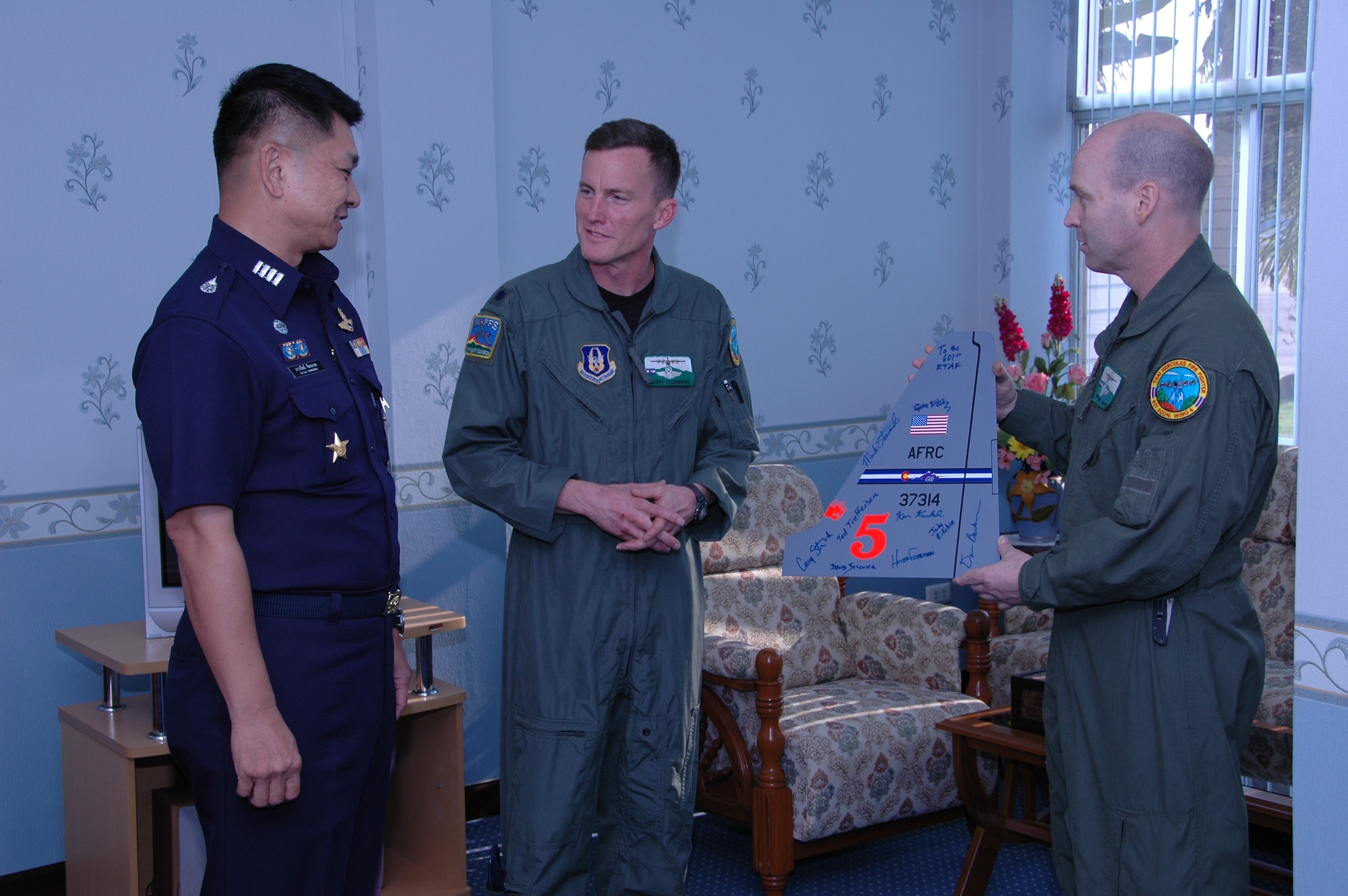 Lt. Col. Corey L. Steinbrink, mission commander (center), and Chief Master Sgt. James D. Riley, chief loadmaster (right), with the Air Force Reserve’s 302nd Airlift Wing, present Special Group Captain (Brig Gen equivalent) Thawonwat Chantanagama, Deputy Director, Director of Operations, Royal Thai Air Force, with a replica tail flash to recognize completion of Modular Airborne Firefighting System training.  The bright orange number “5” on the tail flash signifies the MAFFS unit number flown in the aircraft.  More than 50 members of the RTAF attended the 302 AW-led training to increase their proficiency with the MAFFS system.  Seven 302 AW members traveled to Thailand to provide expert training on safe and effective C-130 MAFFS operations.  This event marks the first time the Air Force Reserve has sent delegates to train a foreign Air Force on use of the MAFFS equipment.  (U.S. Air Force photo/Capt. Jody L. Ritchie)