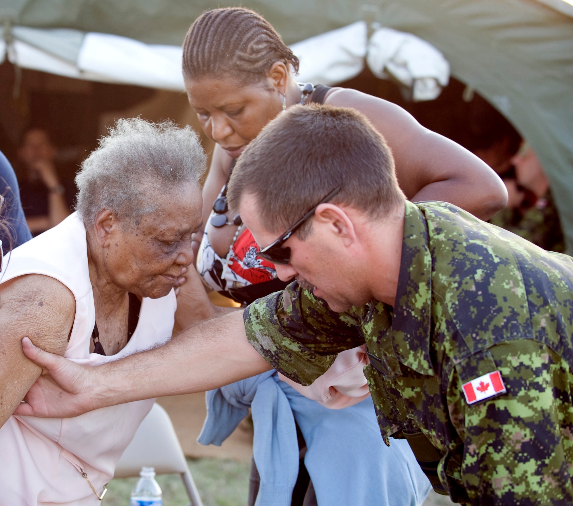 PORT-AU-PRINCE, Haiti -- Canadian Capt. Roderyck Zeaton, 21st Operations Support Squadron (right) assists an elderly woman after she and her family arrived in the Canadian camp at Toussaint Louverture International Airport, Haiti, Jan. 20. Captain Zeaton is a section commander with the 21st OSS, deployed with the Canadian earthquake relief effort to Haiti. While in Haiti, Captain Zeaton is helping establish air traffic control, and was the first-ever air traffic controller at Jacmel airport, a previously uncontrolled airport now receiving humanitarian flights. He was hand-selected for the deployment to provide air traffic control, part of the 21st OSS mission. (Canadian Forces image by Cpl. Julie Bélisle)