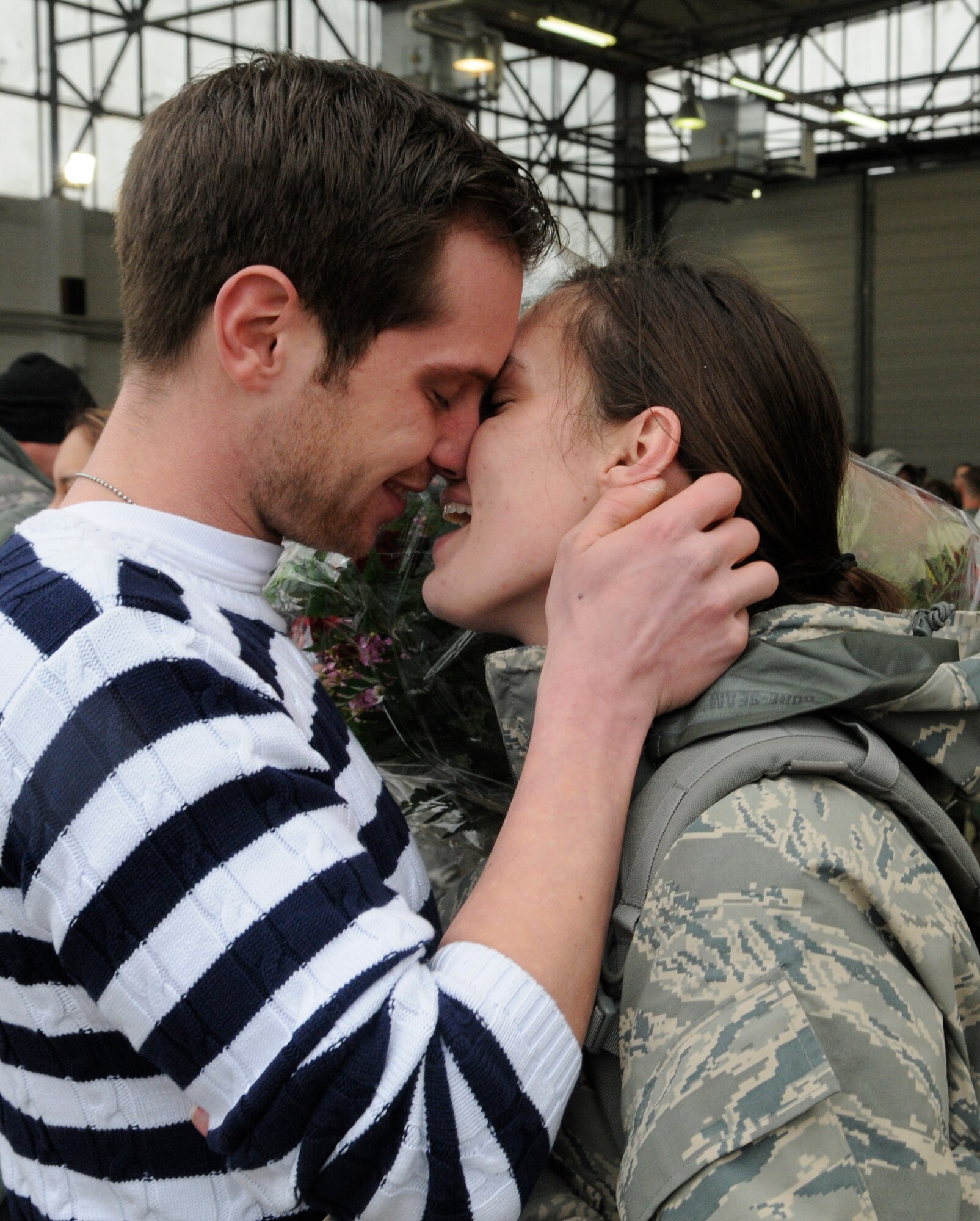 SPANGDAHLEM AIR BASE, Germany – Kai Dahm greets his wife, Staff Sgt. Kimberly Dahm, 23rd Fighter Squadron, with kisses and flowers in Hangar 3 as she returns from her deployment Feb. 5. More than 300 members returned to Spangdahlem after a four-and-a-half month deployment to Joint Base Balad, Iraq, in support of Operation Iraqi Freedom. (U.S. Air Force photo/Senior Airman Benjamin Wilson)
