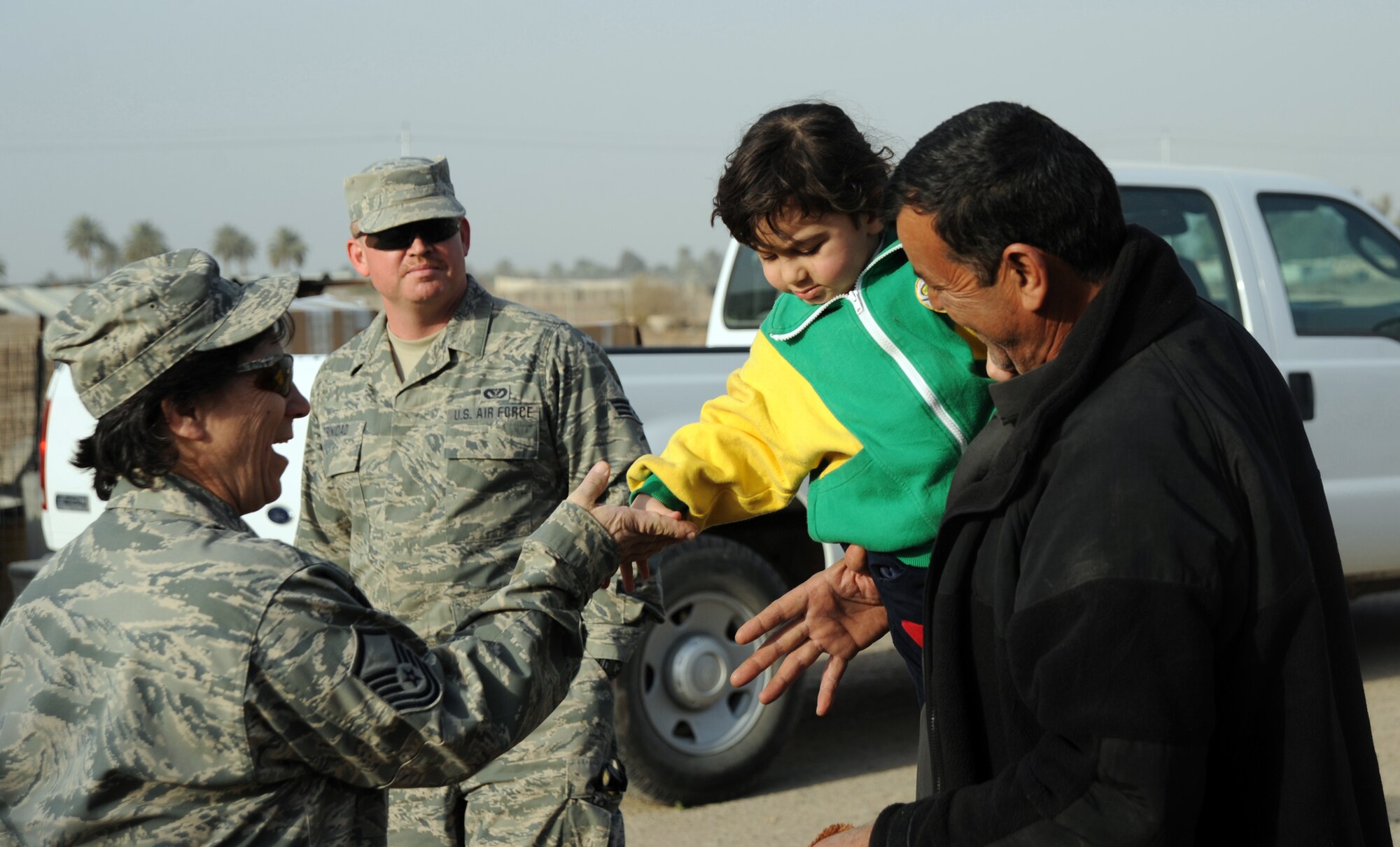 Master Sgt. Margaret Triboletti hands an Iraqi child a piece of candy Jan. 29, 2010, near Sather Air Base, Iraq, while volunteering with the Sather AB good neighbor program. Sergeant Triboletti is assigned to the , 447th Expeditionary Civil Engineer Squadron. (U.S. Air Force photo/Senior Airman Eric Summers Jr.)