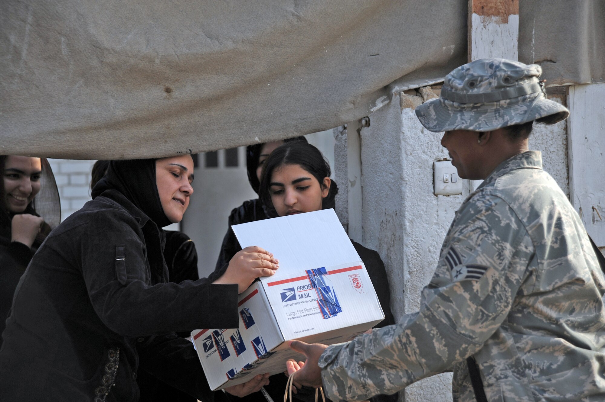 Senior Airman Brena Wilkerson hands out packages of supplies to an Iraqi girl Jan. 29, 2010, near Sather Air Base, Iraq, as part of the Sather AB Rising Six good neighbor program. Airman Wilkerson is assigned to the 447th Expeditionary Communications Squadron. (U.S. Air Force photo/Senior Airman Eric Summers Jr.)