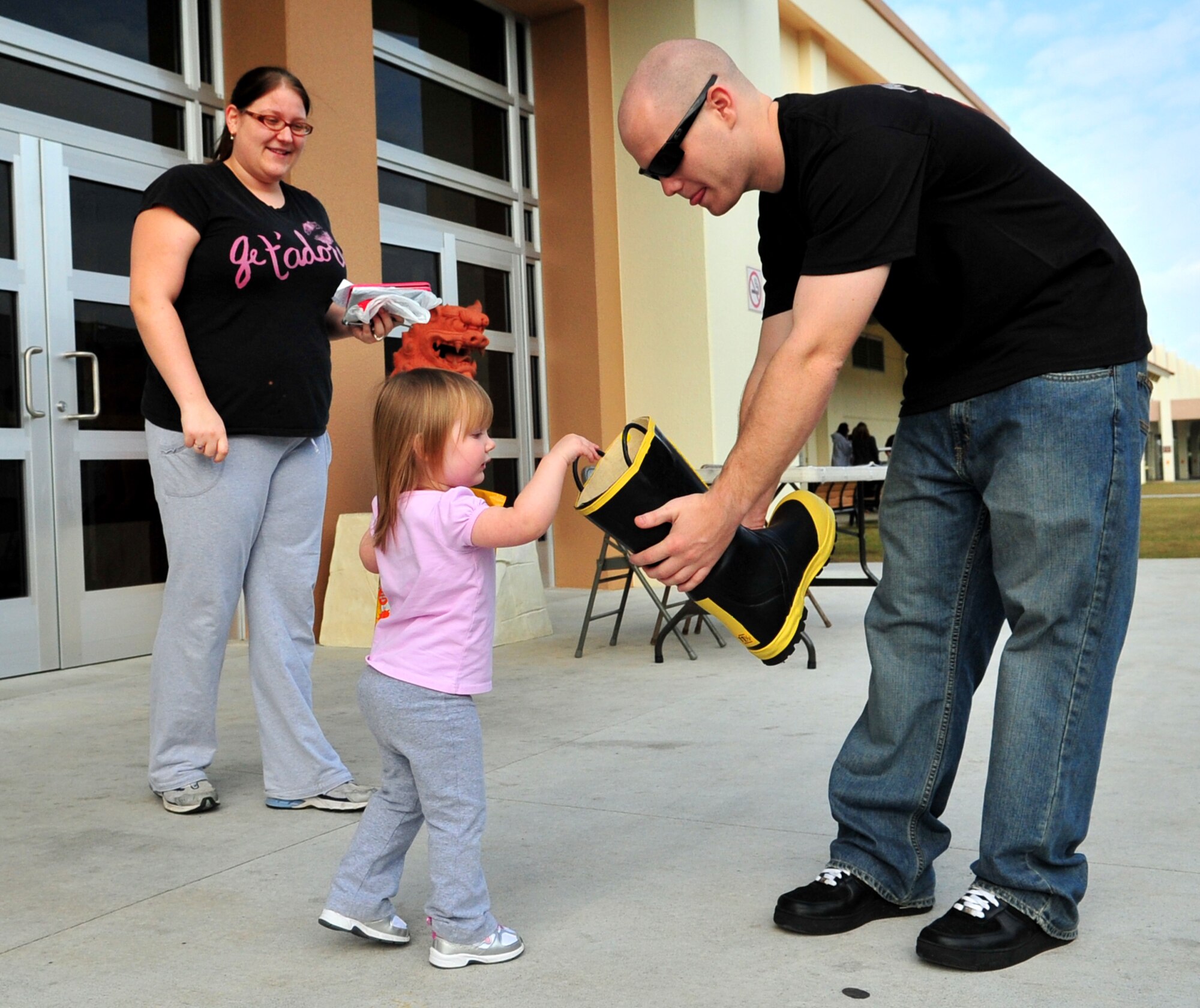 Airman 1st Class Vincent Frasier from the Kadena Fire Department, receives a donation from Logan K. Hutton, 3 years old, during the "Fill the Boot" Haitian relief fund Jan. 30, 2010. The fire department raised a total of $3K last weekend. (U.S. Air Force photo/Tech. Sgt. Rey Ramon)    