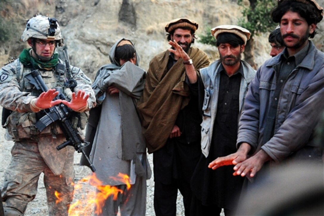 A U.S. soldier warms his hands by a fire made by Afghans during Operation Wawraa Tufaan in Zanbar province, Afghanistan, Jan. 31, 2010. The soldier is assigned to the 25th Infantry Division's Company D, 1st Battalion, 501st Infantry Regiment, 4th Brigade Combat Team.