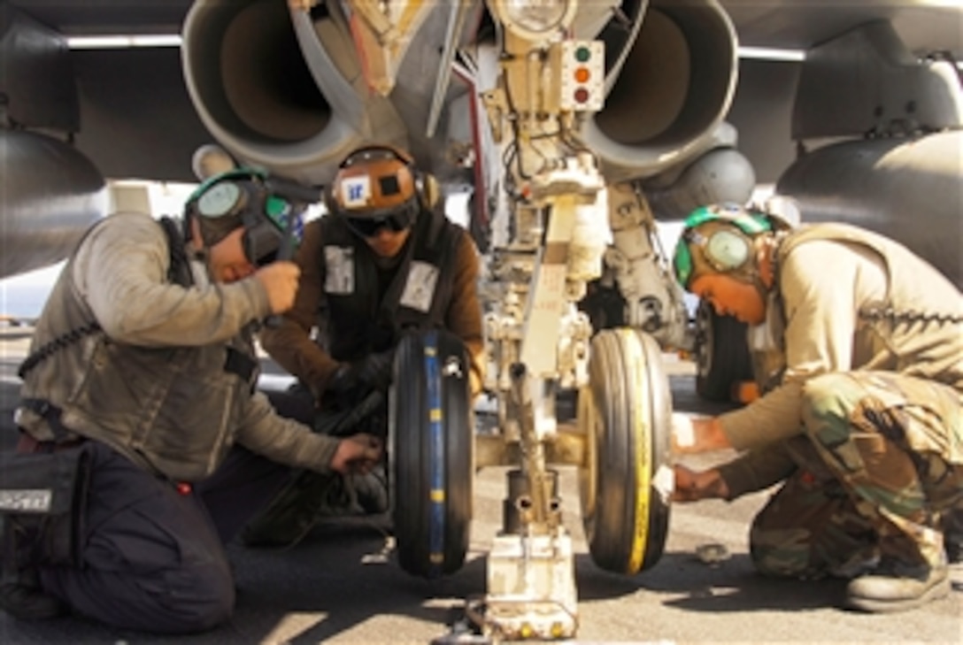 U.S. Navy sailors assigned to Strike Fighter Squadron 97 change the tires on the nose landing gear of an F/A-18C Hornet aircraft aboard the aircraft carrier USS Nimitz (CVN 68) underway in the Indian Ocean on Jan. 28, 2010.  The Nimitz Carrier Strike Group is conducting operations in the U.S. 7th Fleet area of responsibility in support of maritime security.  