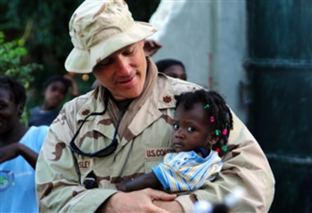 U.S. Coast Guard Lt. Cmdr. Jay Wamsley holds a Haitian toddler in Laogane, Haiti, during a humanitarian visit to multiple small villages outside Port-Au-Prince on Feb. 2, 2010.  Wamsley, an environmental health and safety officer, is temporarily assigned to Port Security Unit 307.  Members of Port Security Unit 307 visited a Haitian orphanage and charity run by Coast Guard Chief Petty Officer Paul Cormier to donate food and lift the spirits of the children.  An estimated 400 people received food donated by Port Security Unit 307.  