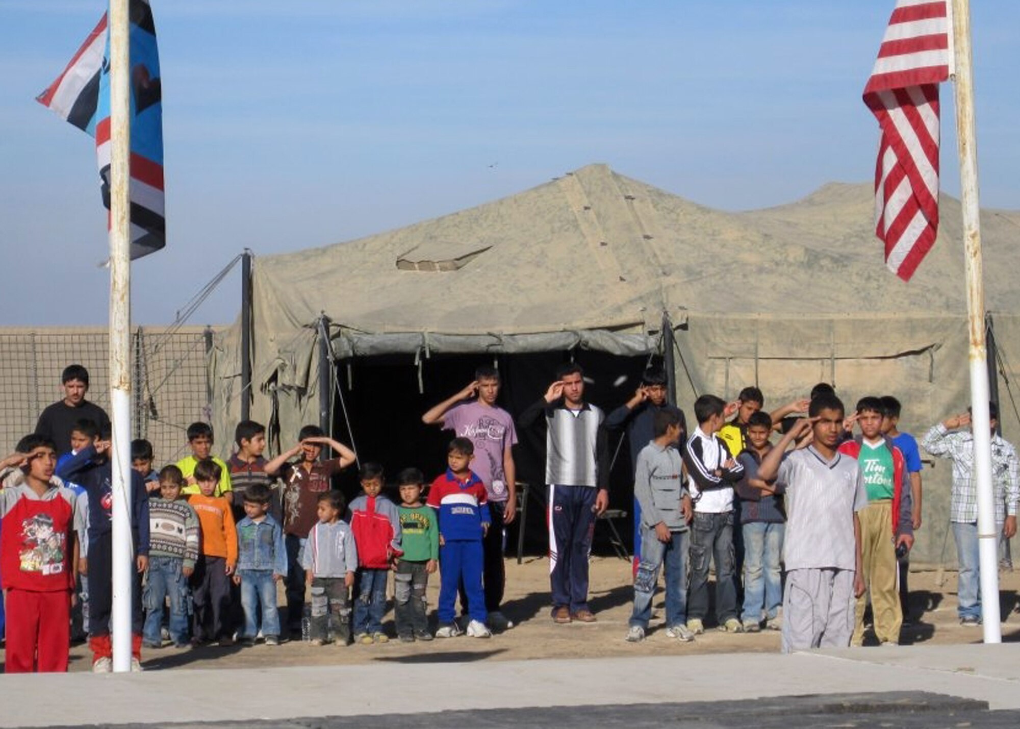 The Iraqi Boy Scouts from Baghdad give a boy scout salute to both the U.S. and Iraqi Boy Scout flag. The boy scouts got to visit the Camp Victory Complex weather station while visiting with U.S. Air Force and Army personnel.  (Courtesy Photo) 