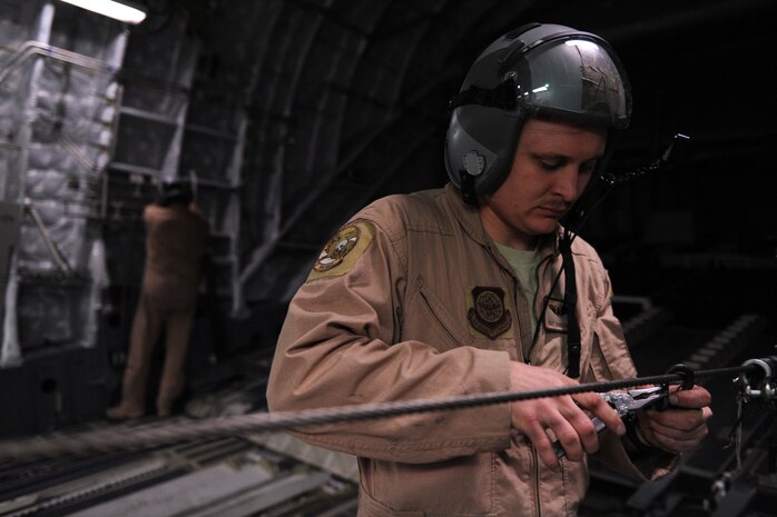 Staff Sgt. Chris Rapp, a C-17 Globemaster III loadmaster assigned to the 816th Expeditionary Airlift Squadron, removes hooks used to deploy parachutes attached to supplies dropped over Afghanistan, Feb. 1, 2010.  (U.S. Air Force photo/Staff Sgt. Manuel J. Martinez/released)
