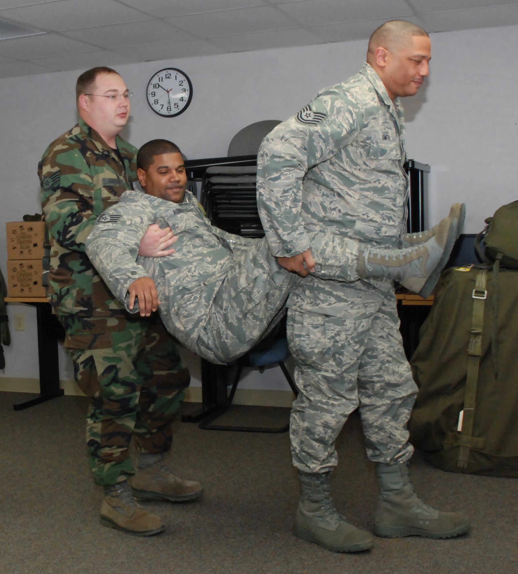 Staff Sgt. Rocky Hancock, 80th Aerial Port Squadron Self-Aid Buddy Care instructor (left), assisted by Staff Sgt. Steve Smith, 94th AW chaplain's assistant, demonstrate the correct technique of performing the Fore-and-Aft Carry.  Staff Sgt. Keith Roberts, 94th Finance specialist, pays the part of the injured Airman.

The Fore-and-Aft Carry is a two-man carry technique for assisting an injured Airman in an emergency situation.  (U.S. Air Force photo/Master Sgt. Stan Coleman)
