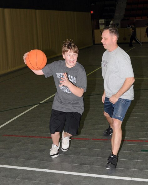 Tom Hermann Jr. takes his dad, Tom Hermann Sr. to the hole while playing basketball at the Winter blast held at the Long Lines Rec. Center and hosted by the 185 Air Refueling Wing Bats Club.