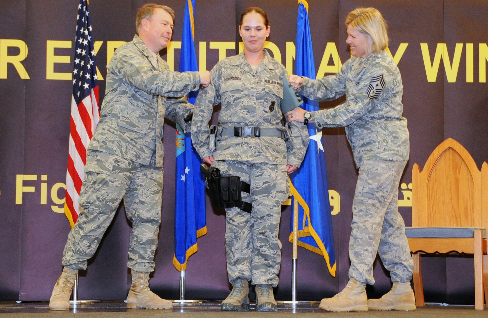 Brig. Gen. Bryan Benson (left), 380th Air Expeditionary Wing commander, and Chief Master Sgt. Suzan Sangster, 380th AEW command chief, tack new stripes on Tech. Sgt. Carrie Ann Richardson of the 380th Expeditionary Security Forces Squadron at a  base in Southwest Asia Feb. 1.  Sergeant Richardson was promoted to technical sergeant through the Stripes for Exceptional Performers Program by Electronic Systems Center Commander Lt. Gen. Ted Bowlds.  Sergeant Richardson is deployed from the 66th Security Forces Squadron at Hanscom AFB.  (U.S. Air Force Photoby Senior Airman Jenifer Calhoun)

 
