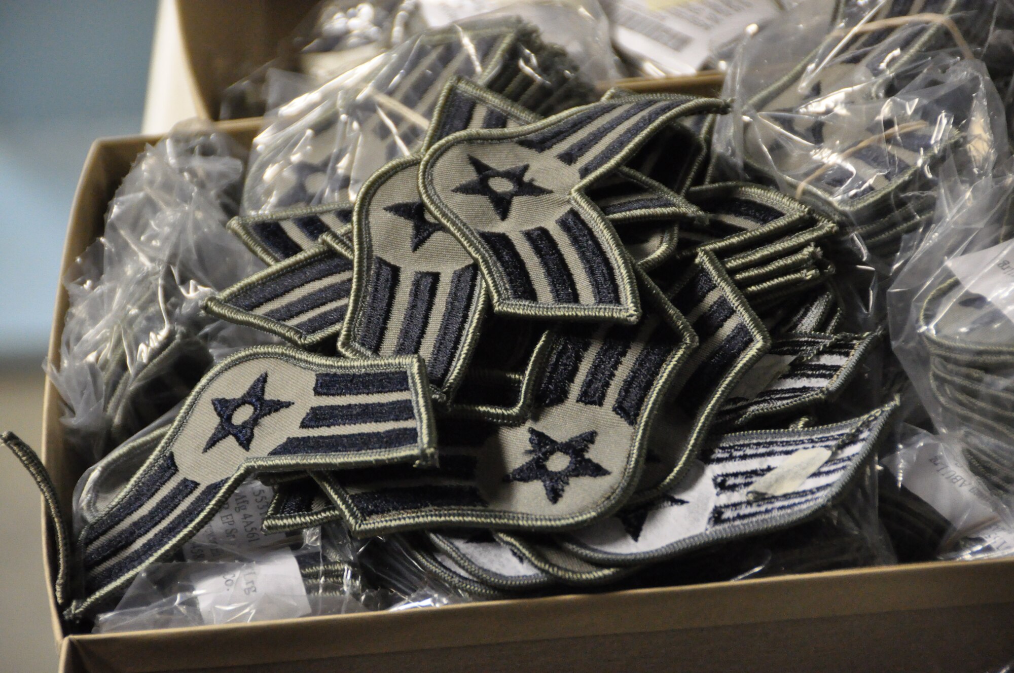 A box of ABU Senior Airman stripes awaits distribution in the supply warehouse at the 128th Air Refueling Wing.  Since the summer of 2009, Airmen at Milwaukee’s Air Guard Wing have been transitioning from the Battle Dress Uniform to the ABU.  Over 900 Airmen will receive 4 complete sets of the new uniform. (US Air Force Photo by: SSgt Nathan Wallin)