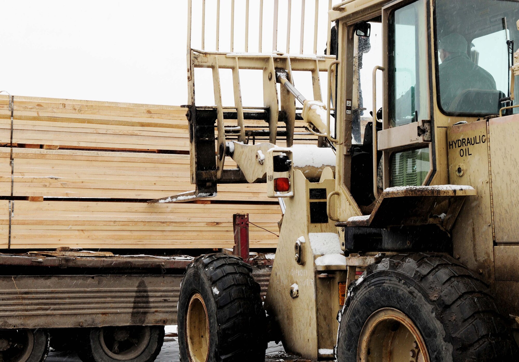U.S. Air Force Tech. Sgt. Mike Meyer, 376th Expeditionary Civil Engineer Squadron resource advisor, unloads a Kyrgyz lumber supplier's entire stock of wood onto the Transit Center at Manas, Kyrgyzstan, Feb 3, 2010. The 376th Expeditionary Contracting Squadron here purchased more than 13,000 pieces of lumber to ship to Afghanistan for base buildup. This massive transfer will boost the local economy and help coalition forces downrange. The project was made possible through the collaborative efforts of contracting, security forces, civil engineers, aerial porters, logistics, and many other support agencies on the Transit Center. Look for an upcoming story on the start-to-finish process. (U.S. Air Force photo/Senior Airman Nichelle Anderson/released)