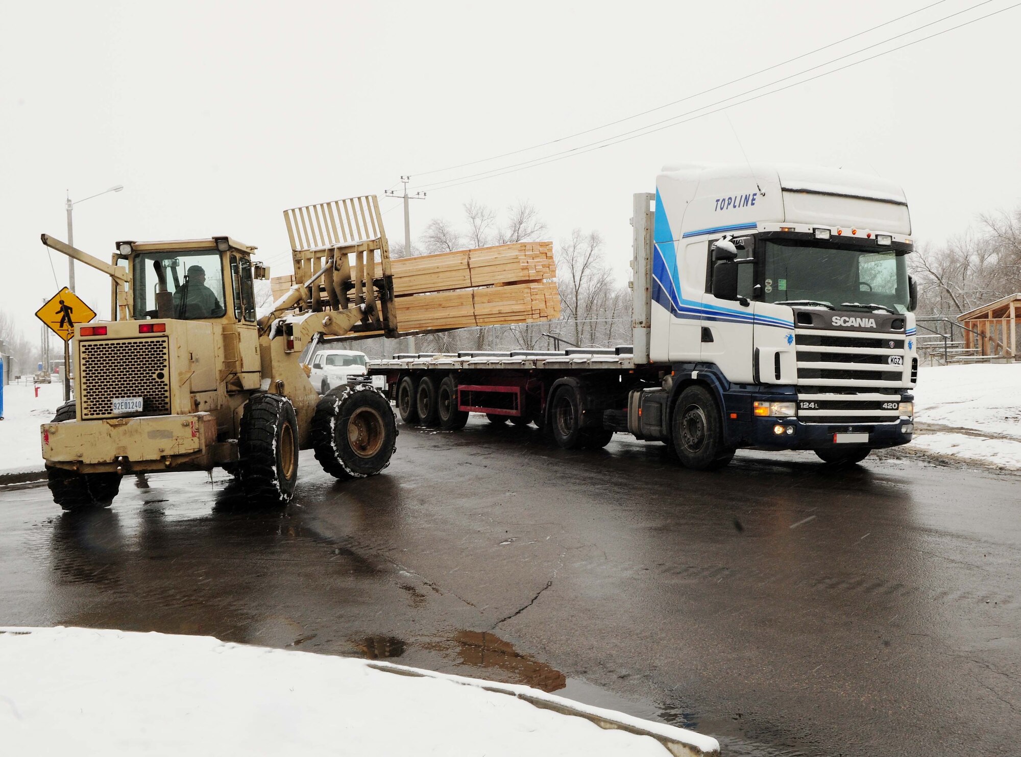 U.S. Air Force Tech. Sgt. Mike Meyer, 376th Expeditionary Civil Engineer Squadron resource advisor, unloads a Kyrgyz lumber supplier's entire stock of wood onto the Transit Center at Manas, Kyrgyzstan, Feb 3, 2010. The 376th Expeditionary Contracting Squadron here purchased more than 13,000 pieces of lumber to ship to Afghanistan for base buildup. This massive transfer will boost the local economy and help coalition forces downrange. The project was made possible through the collaborative efforts of contracting, security forces, civil engineers, aerial porters, logistics, and many other support agencies on the Transit Center. Look for an upcoming story on the start-to-finish process. (U.S. Air Force photo/Senior Airman Nichelle Anderson/released)
