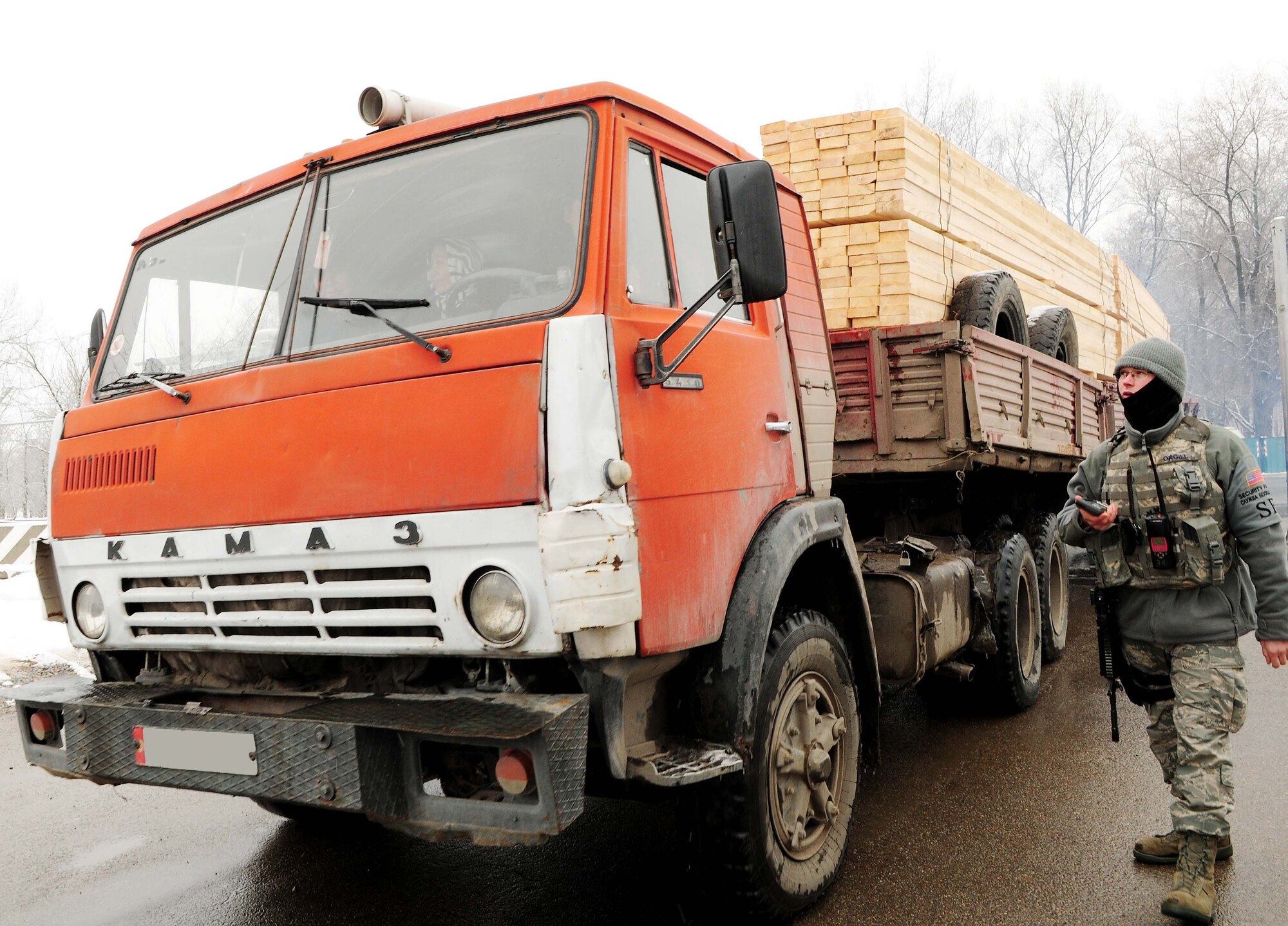 A 376th Expeditionary Security Forces Squadron Airman allows a Kyrgyz lumber supplier through the front gate of the Transit Center at Manas, Kyrgyzstan, Feb 3, 2010. The 376th Expeditionary Contracting Squadron here purchased more than 13,000 pieces of lumber - the local company's entire stock - to ship to Afghanistan for base buildup. This massive transfer will boost the local economy and help coalition forces downrange. The project was made possible through the collaborative efforts of contracting, security forces, civil engineers, aerial porters, logistics, and many other support agencies on the Transit Center. Look for an upcoming story on the start-to-finish process. (U.S. Air Force photo/Senior Airman Nichelle Anderson/released)