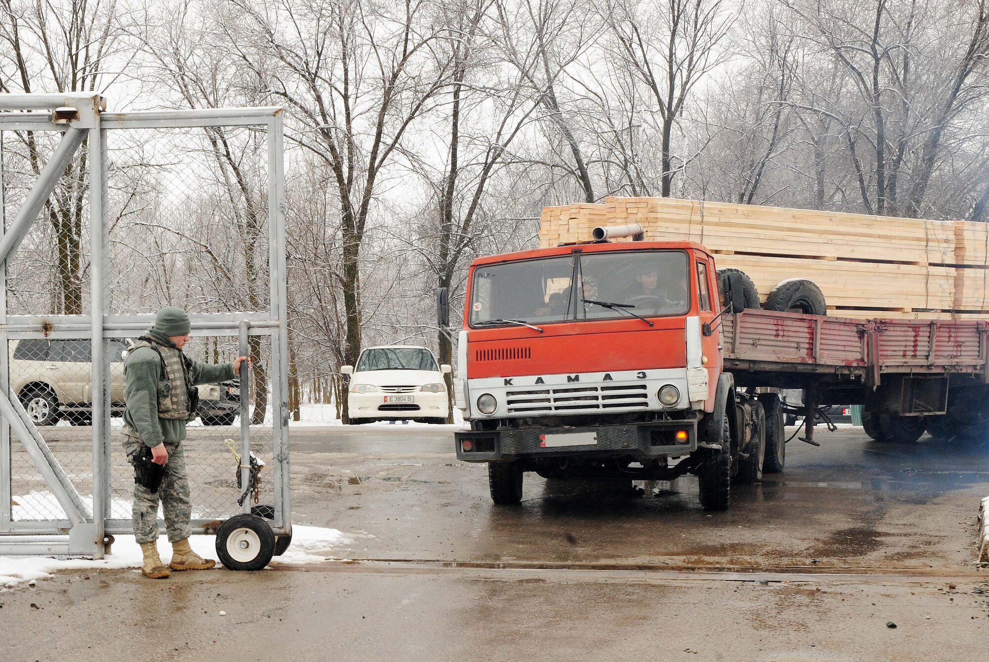 A 376th Expeditionary Security Forces Squadron Airman allows a Kyrgyz lumber supplier through the front gate of the Transit Center at Manas, Kyrgyzstan, Feb 3, 2010. The 376th Expeditionary Contracting Squadron here purchased more than 13,000 pieces of lumber - the local company's entire stock - to ship to Afghanistan for base buildup. This massive transfer will boost the local economy and help coalition forces downrange. The project was made possible through the collaborative efforts of contracting, security forces, civil engineers, aerial porters, logistics, and many other support agencies on the Transit Center. Look for an upcoming story on the start-to-finish process. (U.S. Air Force photo/Senior Airman Nichelle Anderson/released)