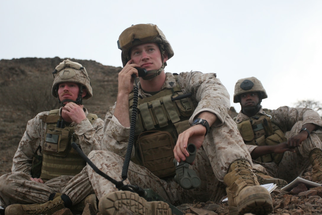 Sergeant Briss Miller (center), from Java, N.Y., calls for fire while his fellow Marines from the 11th Marine Expeditionary Unit’s 1st Air Naval Gunfire Liaison Company detachment, Sgt. Matthew Oudbier (left), from Grand Rapids, Mich., and Cpl. Vaughn Johnson, from Kansas City, Kan., watch for mortar impacts here Feb 8. The Anglico Marines conducted live-fire exercises with mortars and both fixed and rotary wing aircraft.