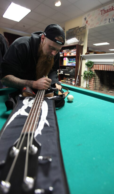 MARINE CORPS BASE CAMP LEJEUNE, N.C.-  Matt Snell, bass guitarist for Five Finger Death Punch, signs a guitar for a wounded warrior during a visit to the Wounded Warrior Battalion-East Feb. 9.