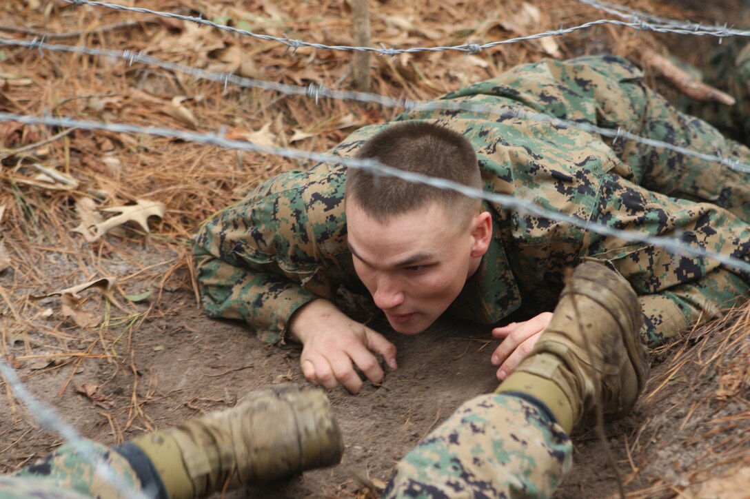 MARINE CORPS BASE CAMP LEJEUNE, N.C. – A corporal with Headquarters and Support Battalion, Marine Corps Base Camp Lejeune low-crawls under a barbed-wire trench during the Corporals Stamina Course aboard Stone Bay, Feb. 9. (Marine Corps photo by Lance Cpl. Jonathan G. Wright)