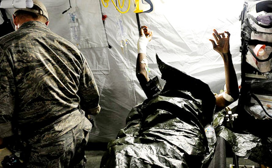 A medical technician from Air Force Special Operations Command checks on Haitian patients in a field clinic Jan. 16, 2010, in Port au Prince, Haiti. (U.S. Air Force photo/Master Sgt. Russell E. Cooley IV)