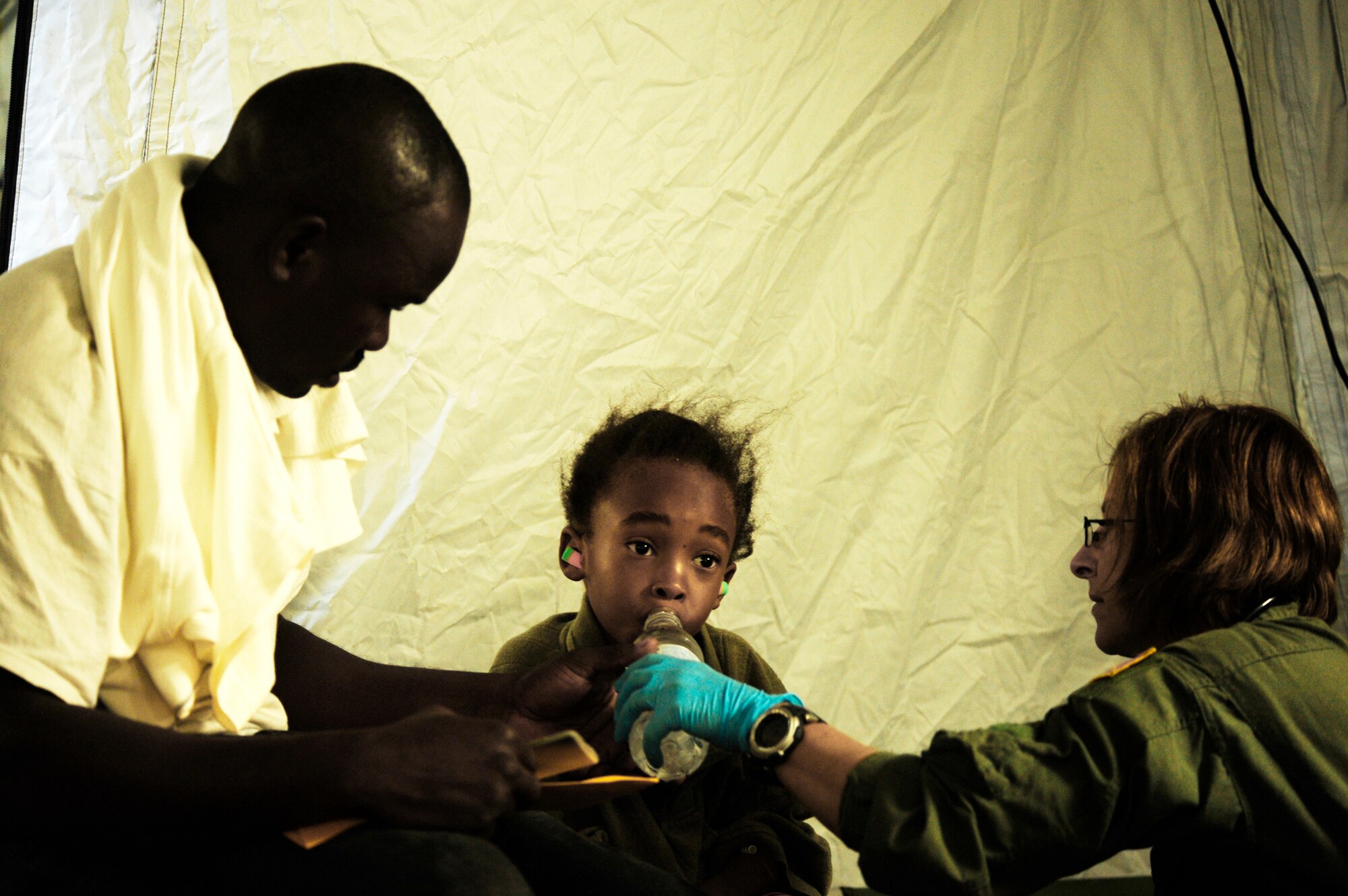 A 6-year-old Haitian boy is given water by a medical technician Jan. 19, 2010 at the Toussaint L'Ouverture International Airport in Port-au-Prince, Haiti. The medical technician is assigned to the 1st Special Operations Support Squadron. (U.S. Air Force photo/Tech. Sgt. James L. Harper Jr.)
