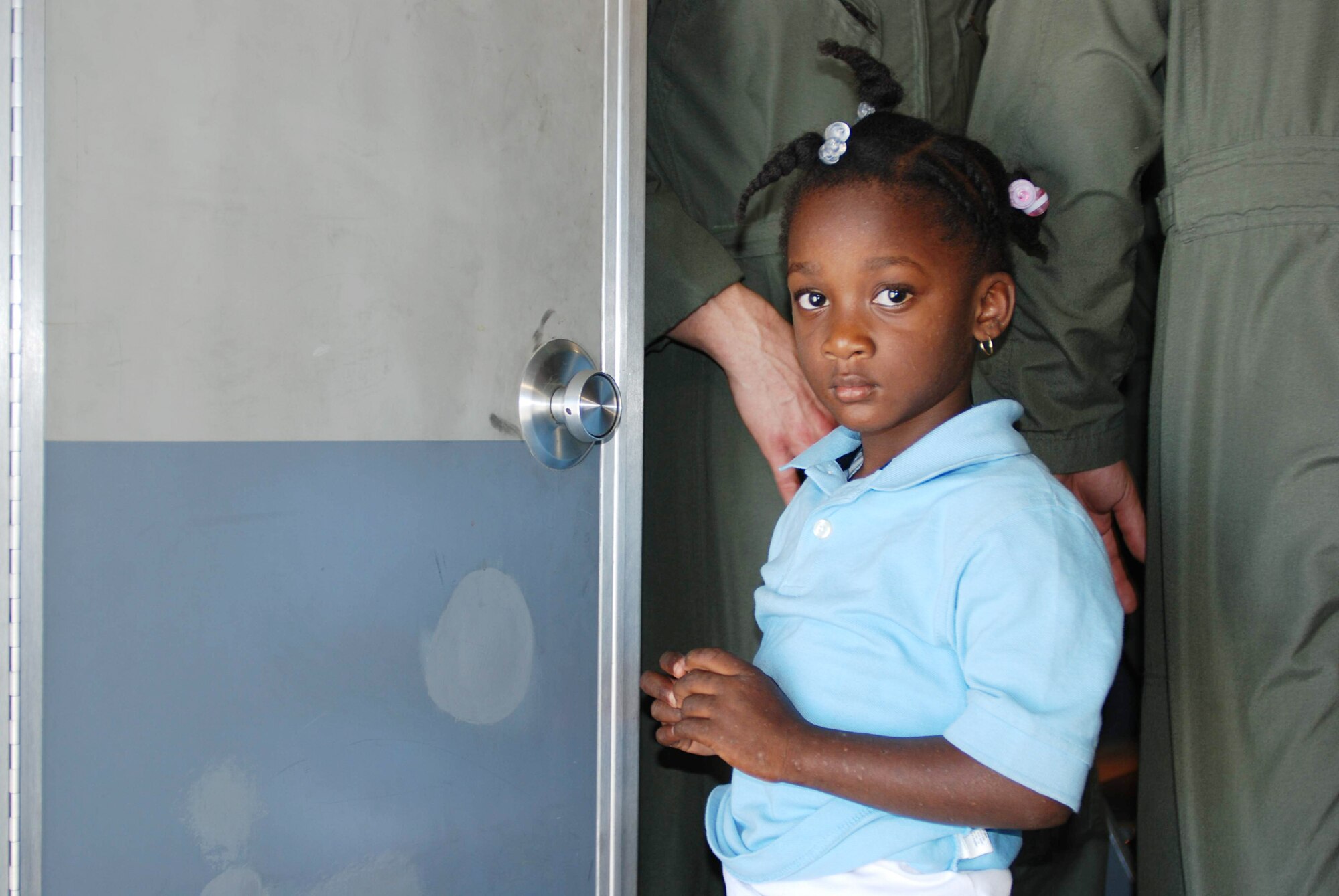 A young girl waits patiently to use the lavatory after boarding a C-17 Globemaster III Jan. 29, 2010, in Port-au-Prince, Haiti. Behind her, two crewmembers from the 729th Airlift Squadron from March Air Reserve Base, Calif., prepare to fly the load of 176 passengers to Orlando Sanford International Airport in Florida. (U.S. Air Force photo/Capt. Ashley Norris)