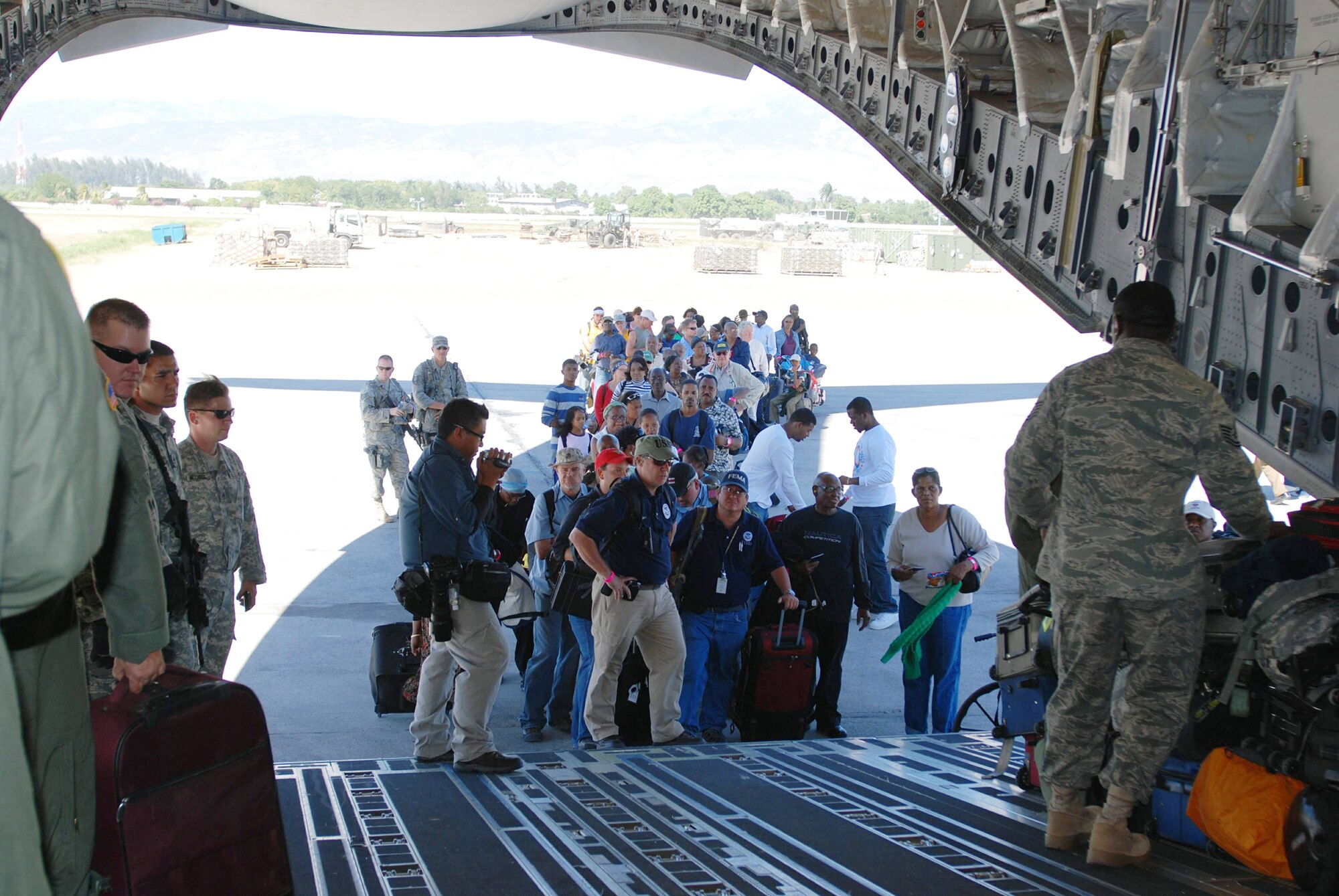 Aid workers and evacuees with U.S. passports and visas wait in line to board a C-17 Globemaster III from March Air Reserve Base, Calif., Jan. 29, 2010, in Port-au-Prince, Haiti. The C-17 flew three missions as part of Operation Unified Response into Haiti, before returning to March ARB Feb. 1. (U.S. Air Force photo/Capt. Ashley Norris)