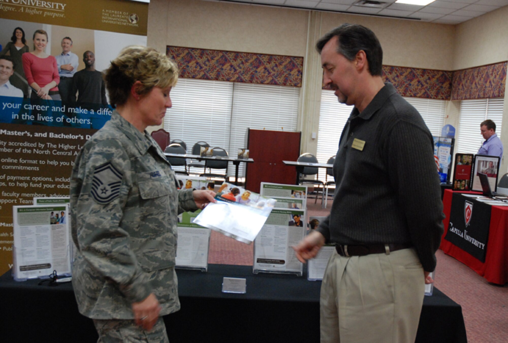 Senior Master Sgt. Joy E. Hughes, chief, 94th Airlift Wing Education and Training, receives enrollment instructions from Rodney Hockenberry, senior field representative for Walden College at the 2010 Education fair at Verhulst Hall here Feb. 6-7. The event was designed to give Airmen the opportunity to speak with experts regarding classroom and online courses, G.I. Bill, military tuition assistance, financial aid and the college application process. (U.S. Air Force photo/Tech. Sgt. James Branch)