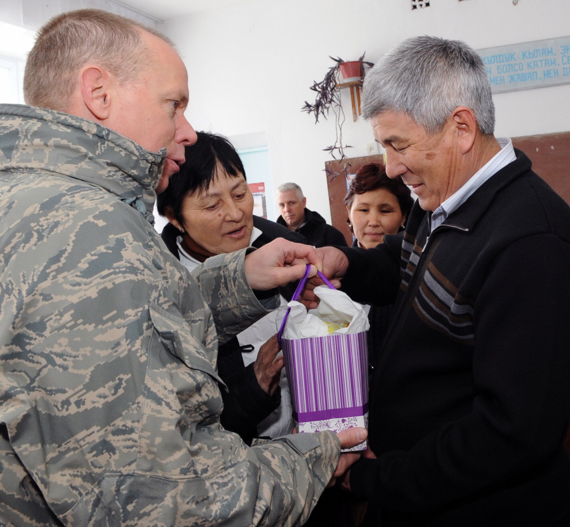 Gen. Donald Hoffman, Commander of Air Force Materiel Command, presents Syrgak Kyolykeer, Head and Mayor of Grozd Village Administration, with a gift from the Transit Center at Manas, Kyrgyzstan, at the Grozd School in Grozd Village, Kyrgyzstan, Feb. 9, 2010. (U.S. Air Force photo/Senior Airman Nichelle Anderson/released)