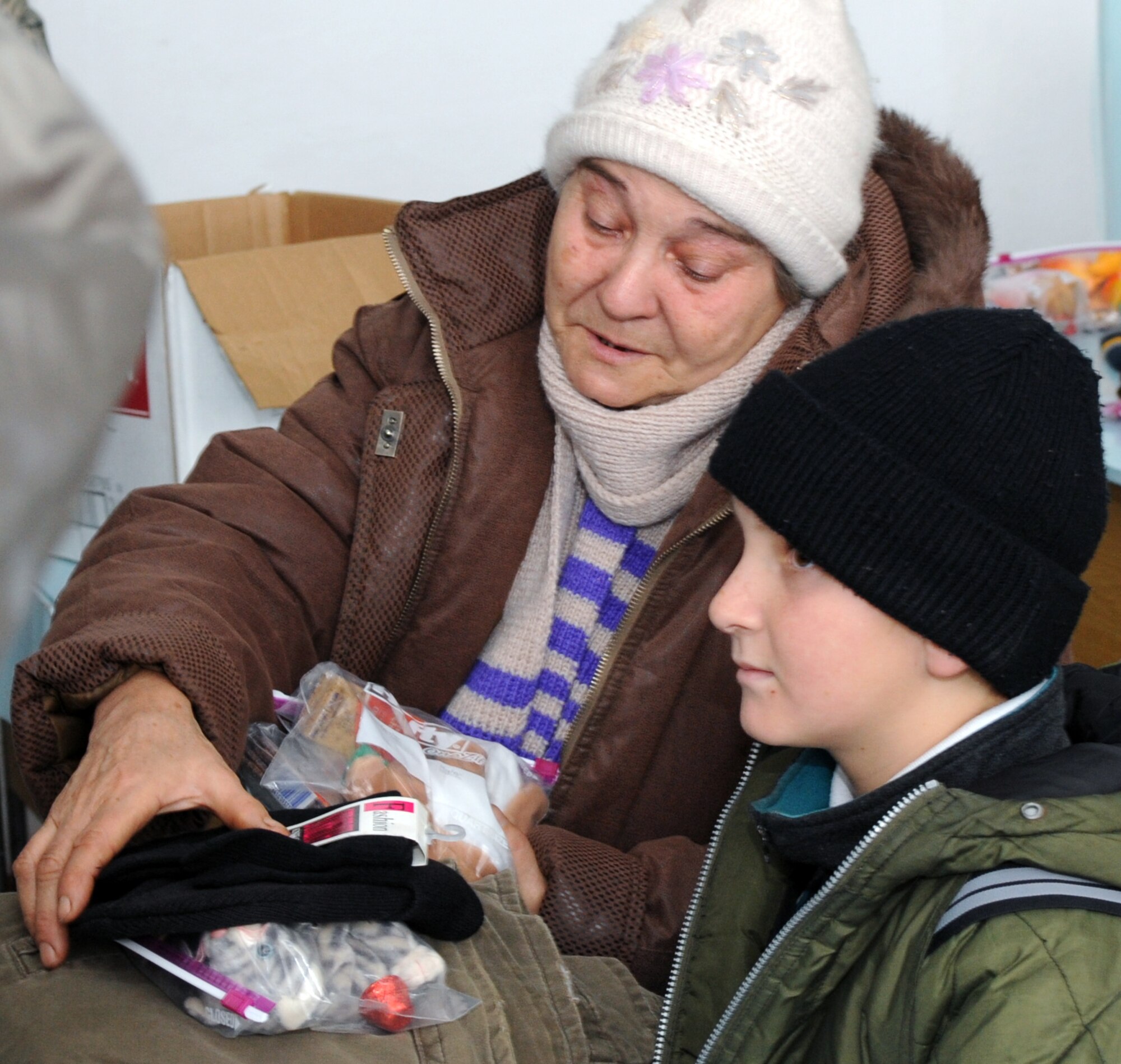 A grateful Kyrgyz mother helps her son as he receives candy and small toys from Airmen from the Transit Center at Manas Feb. 9, 2010. (U.S. Air Force photo/Senior Airman Nichelle Anderson/released)