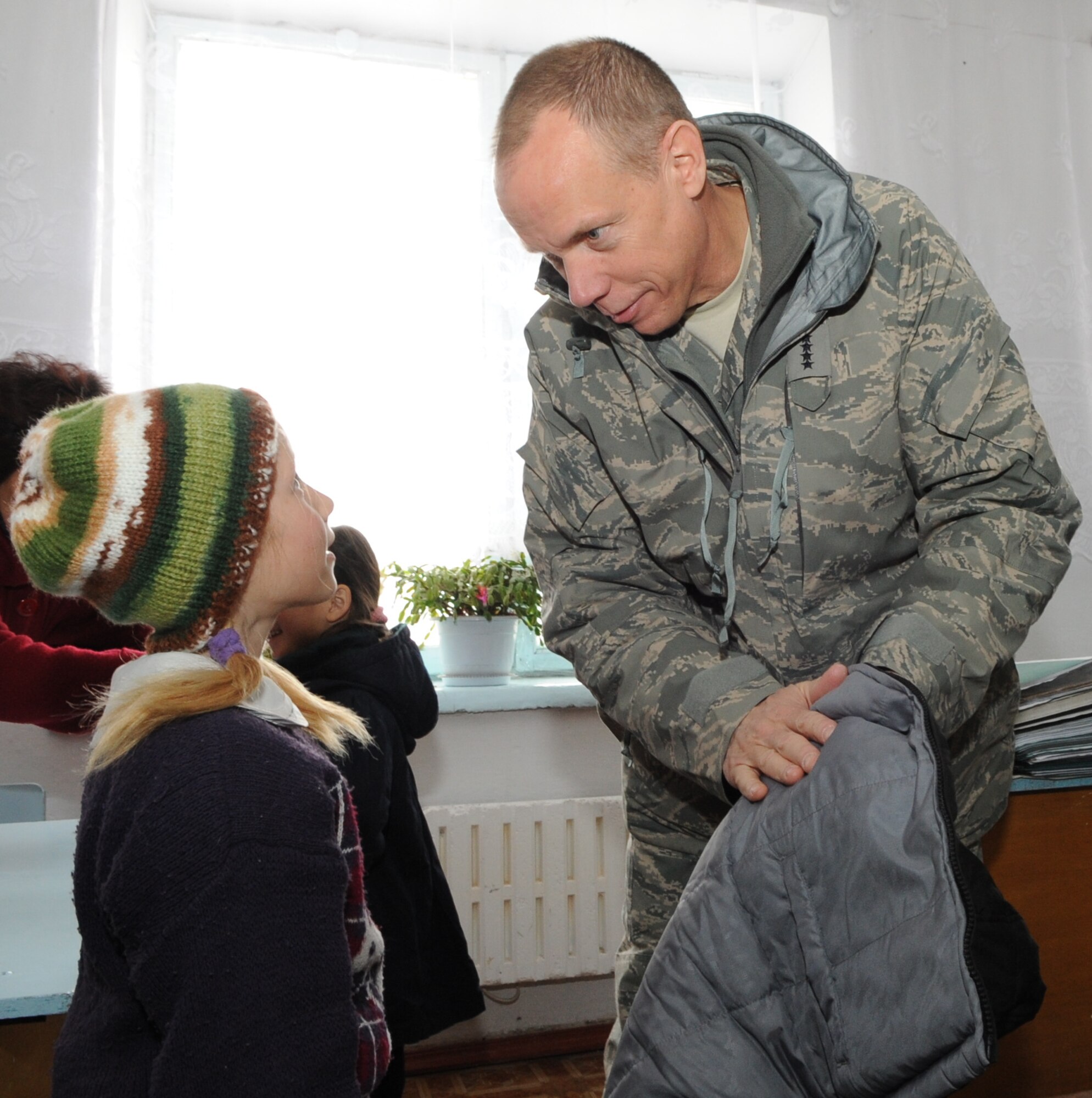 Gen. Donald Hoffman, Commander of Air Force Materiel Command, hands a warm coat to an elementary school girl of the Grozd School in Grozd Village, Kyrgyzstan, Feb. 9, 2010. (U.S. Air Force photo/Senior Airman Nichelle Anderson/released)