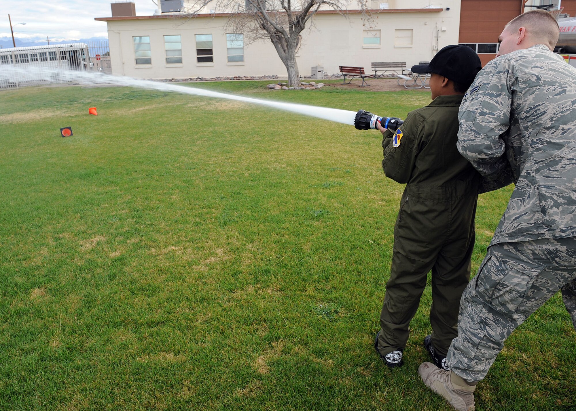 Airman 1st Class Daniel Robinson, 355th Civil Engineer Squadron, helps Markino Mctaggrait hold a water hose steady during his Pilot for a Day tour here Jan. 29. This program is designed for children with serious illnesses and helps them enjoy a day totally devoted to them and their interest in aviation. Markino had a chance to fly in an A-10 simulator, see the base's fire department, aircraft static displays and meet members of the U.S. Air Force.  (U.S. Air Force/Staff Sgt. Jacqueline Romero)
