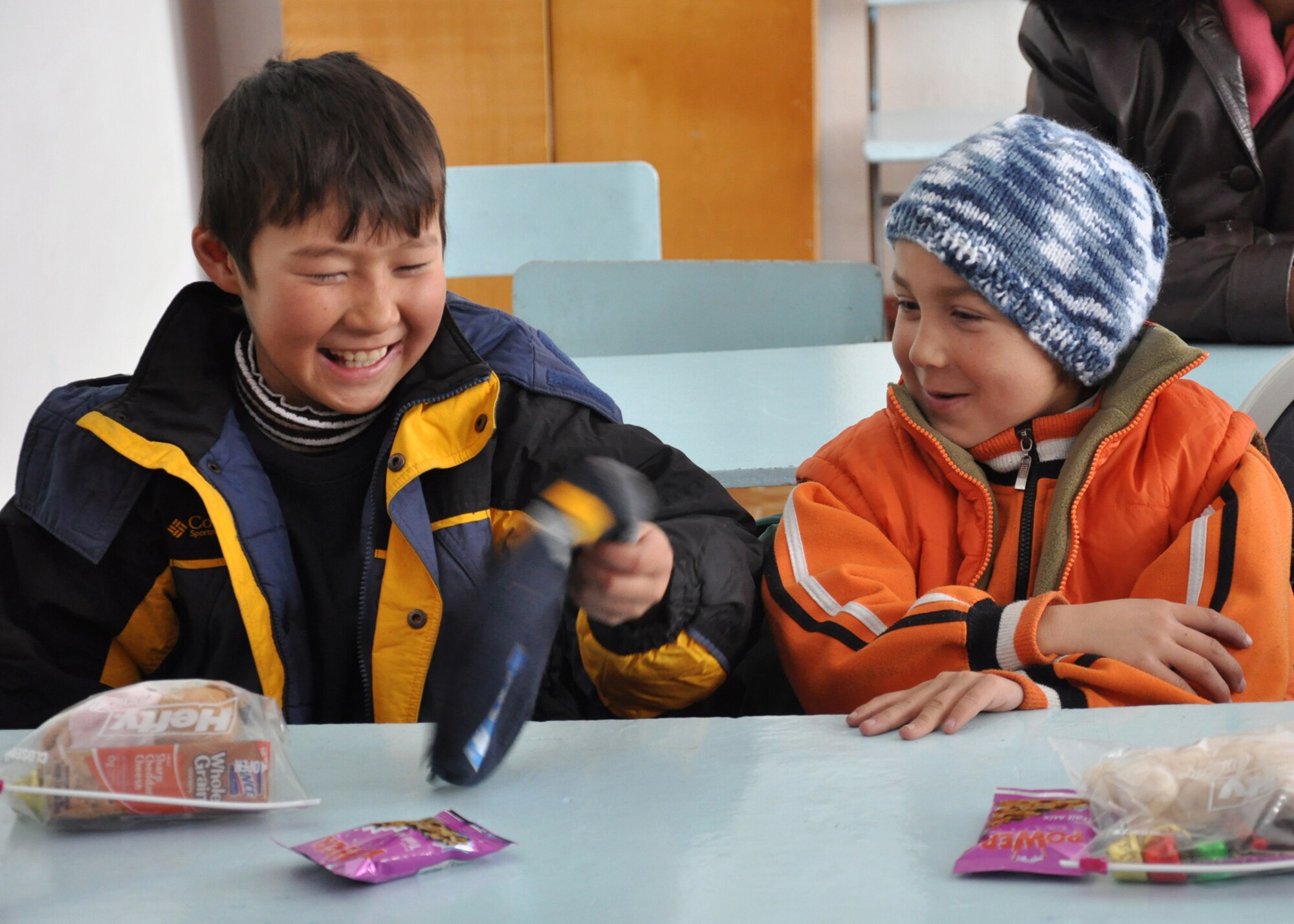 Two elementary school boys from Grozd School in Grozd Village, Kyrgyzstan, joyfully compare gloves and other items they received from Airmen from the Transit Center at Manas Feb. 9, 2010. (U.S. Air Force photo/Staff Sgt. Carolyn Viss/released)