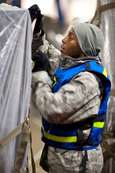 Staff Sgt. Larry Parker, 35th Maintenance Squadron avionics production superintendent, adjusts cargo netting on an aircraft pallet inside Hangar 949 during an operational readiness exercise Jan. 28, 2010, at Misawa Air Base, Japan. Equipment on pallets was tied down with tarps and cargo netting to keep it safe while aboard a cargo aircraft. (U.S. Air Force photo/Staff Sgt. Samuel Morse) 
