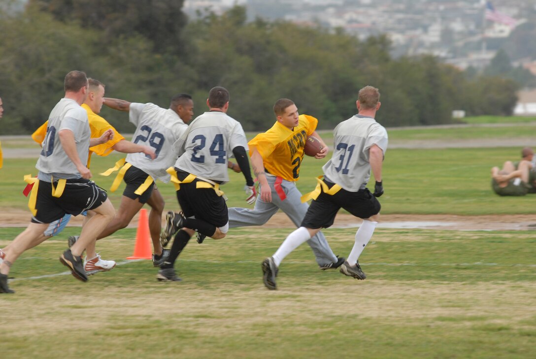 Running back Zach Robbins yellow jersey, hauls through the mass of Coast Guard players and manages to stay untouched long enough to score a first down, during the Commanding Generals Cup Flag Football game at the depot sports field, Feb. 9.