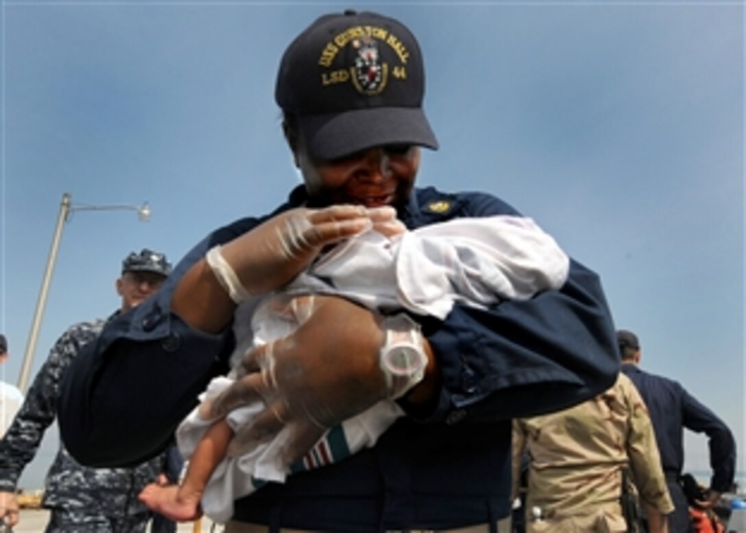 U.S. Navy Seaman Deenicia Canty holds a newborn baby at the Killick Haitian Coast Guard Base in Killick, Haiti, Feb. 5, 2010, after the infant and mother were brought back ashore following their stay aboard the hospital ship USNS Comfort. Canty is a chief quartermaster assigned to the amphibious dock landing ship USS Gunston Hall, which is providing humanitarian relief to Haiti.