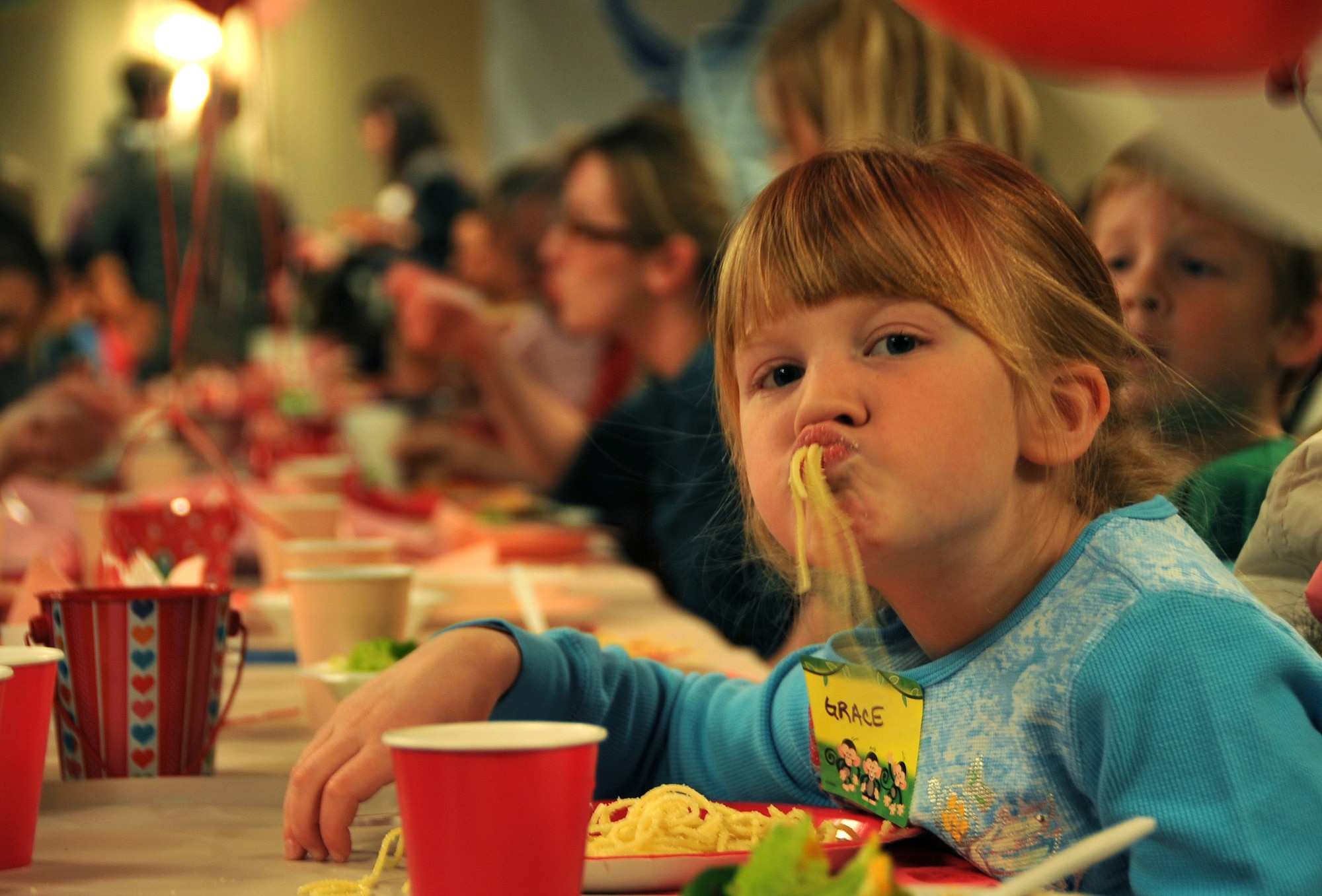 OFFUTT AIR FORCE BASE, Neb. -- Grace Rowe, 7-year-old daughter of 1st Airborne Command Control Squadron member Lt. Col. Mike Rowe, enjoys spaghetti at the deployed family dinner at the community center Feb. 9.  Colonel Rowe is currently deployed. Organizations and volunteers from across Offutt and in the local community come together each quarter to plan an event for the families of deployed military members. This event featured a free dinner and games for children and educational guidance for spouses to help them with separation. U.S. Air Force photo by Jeff W. Gates.